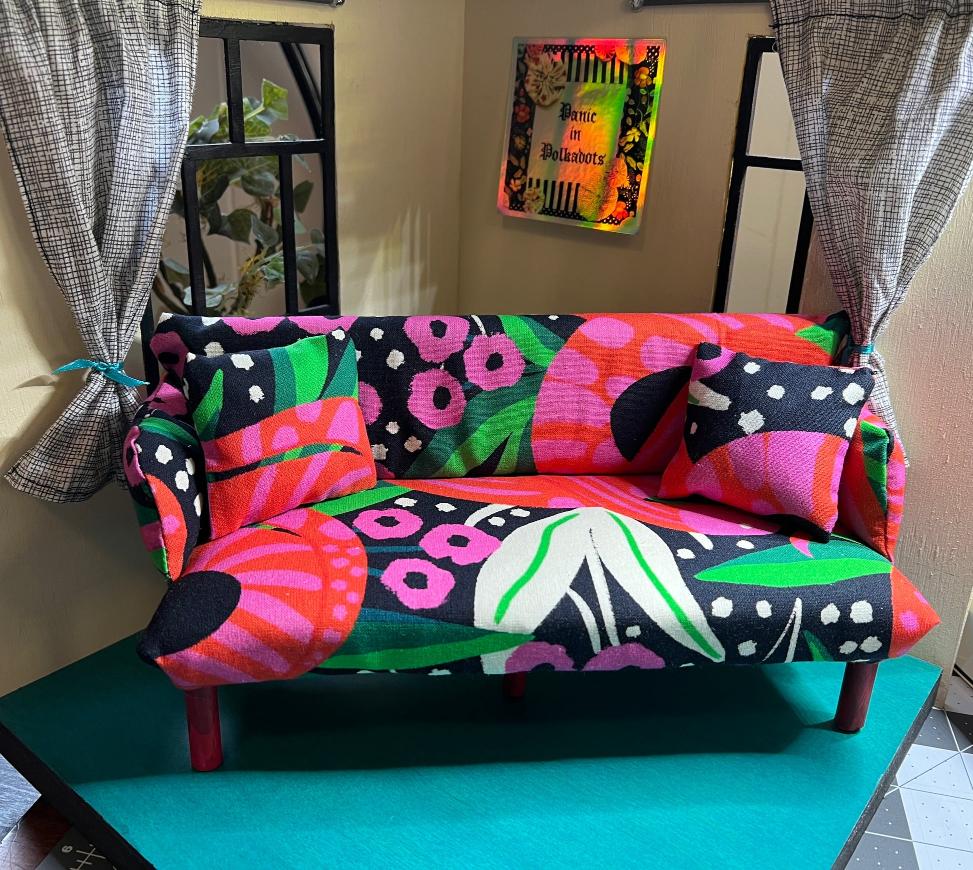 handmade Barbie doll couch, in a dollhouse setting for scale, includes two pillows by Panic in Polkadots. Bright floral snake graphic fabric in pinks, reds, greens, and white and black