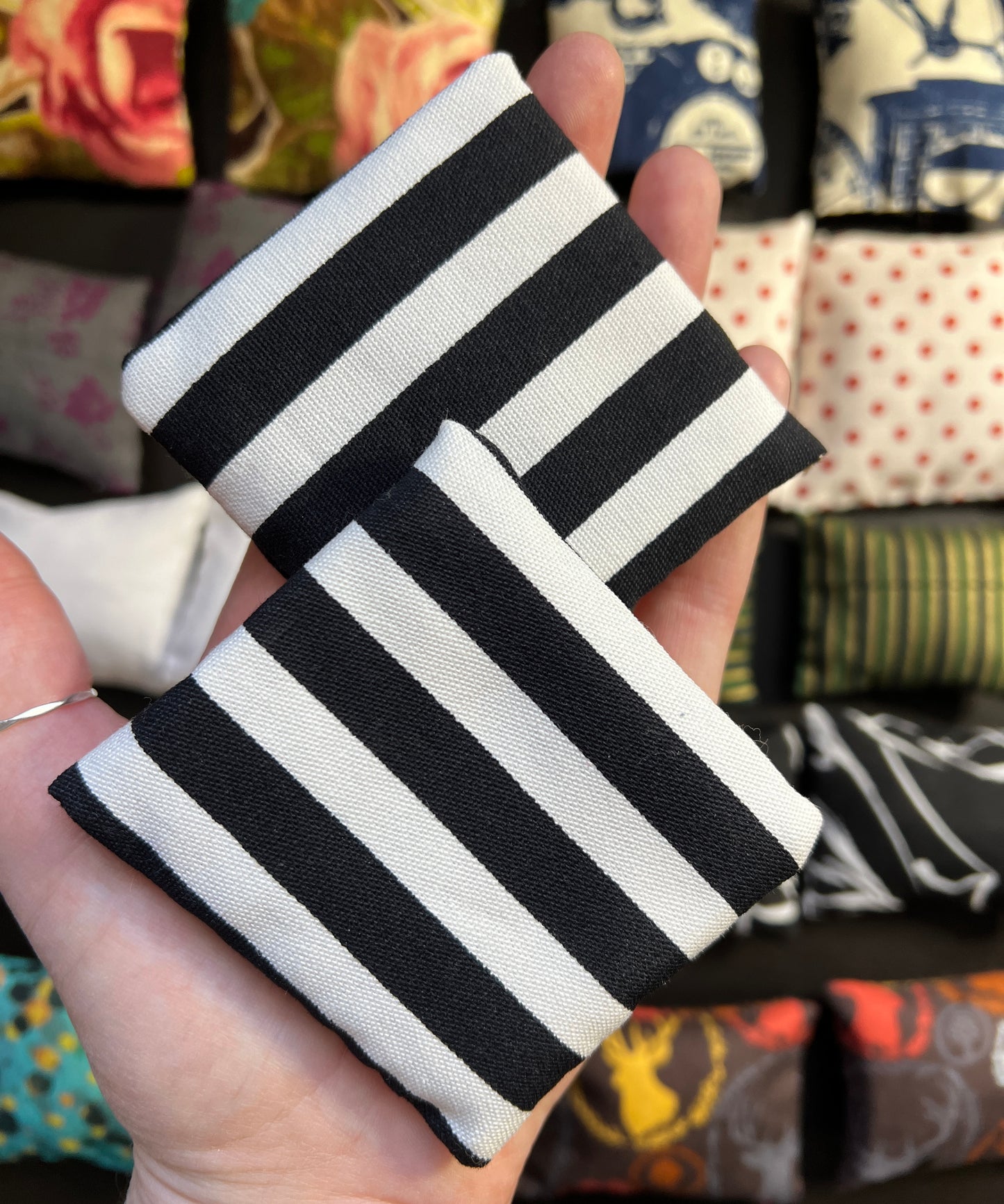 a hand holds a pair of Barbie pillows, for scale. bold stripes in white and black. other pillows in distance