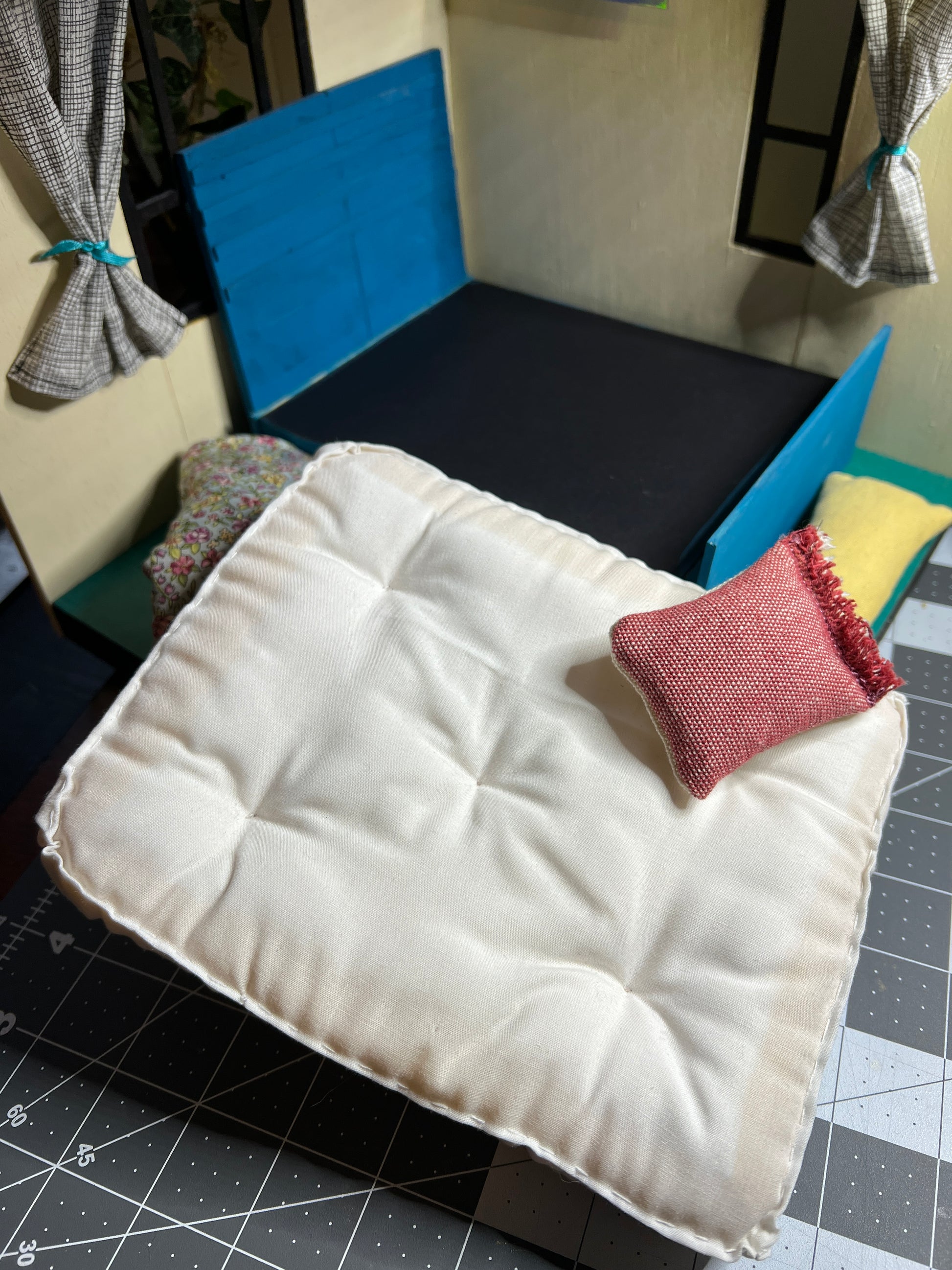 a dollhouse bed frame, with mattress and comforter and pillow