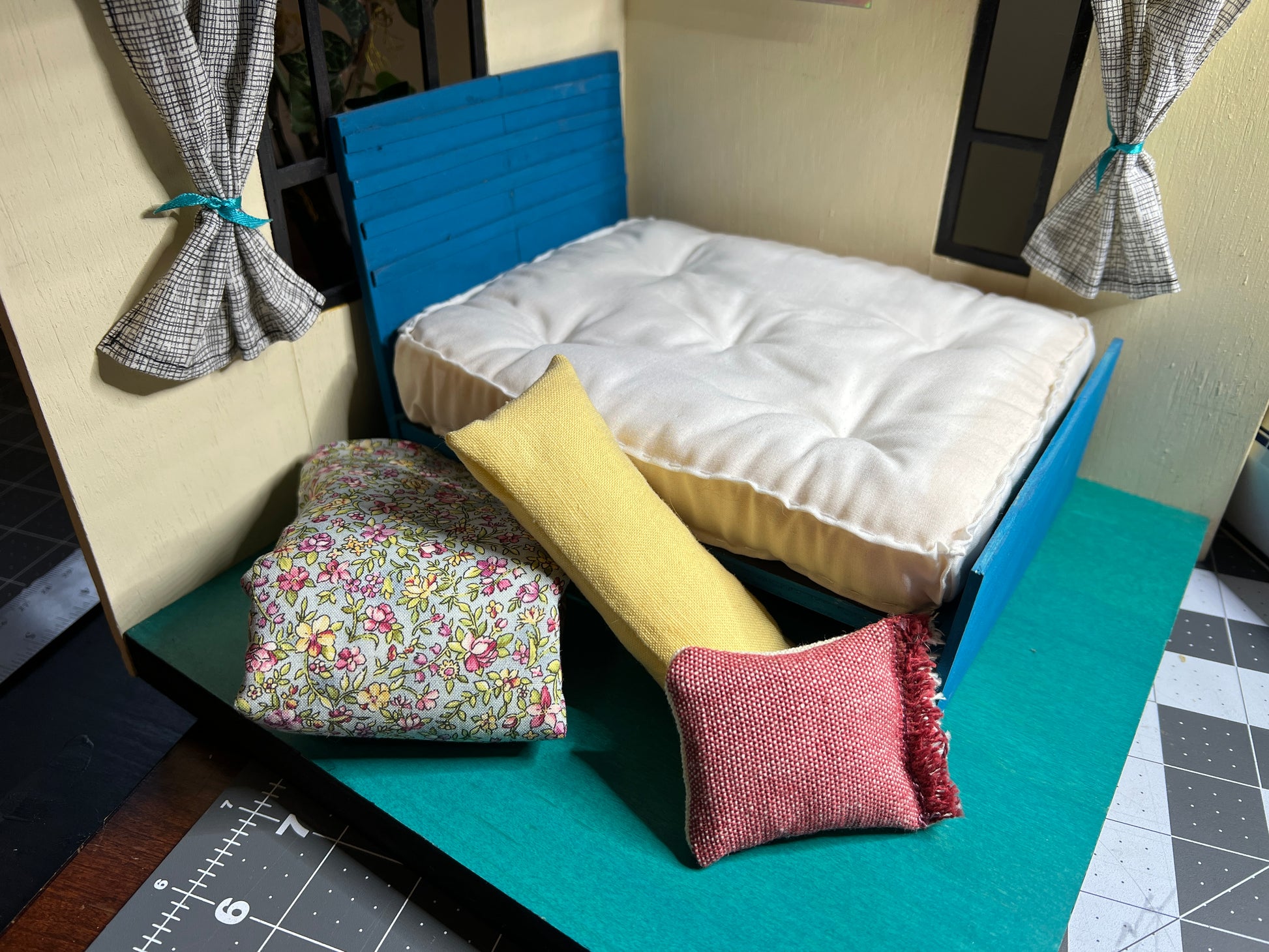 a dollhouse bed frame, with mattress and comforter and pillow in a room diorama for scale and styling