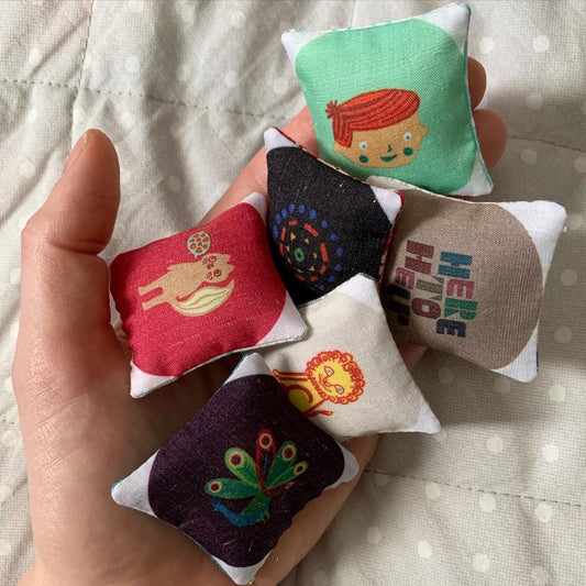a small collection of mini pillows, in a hand for scale
