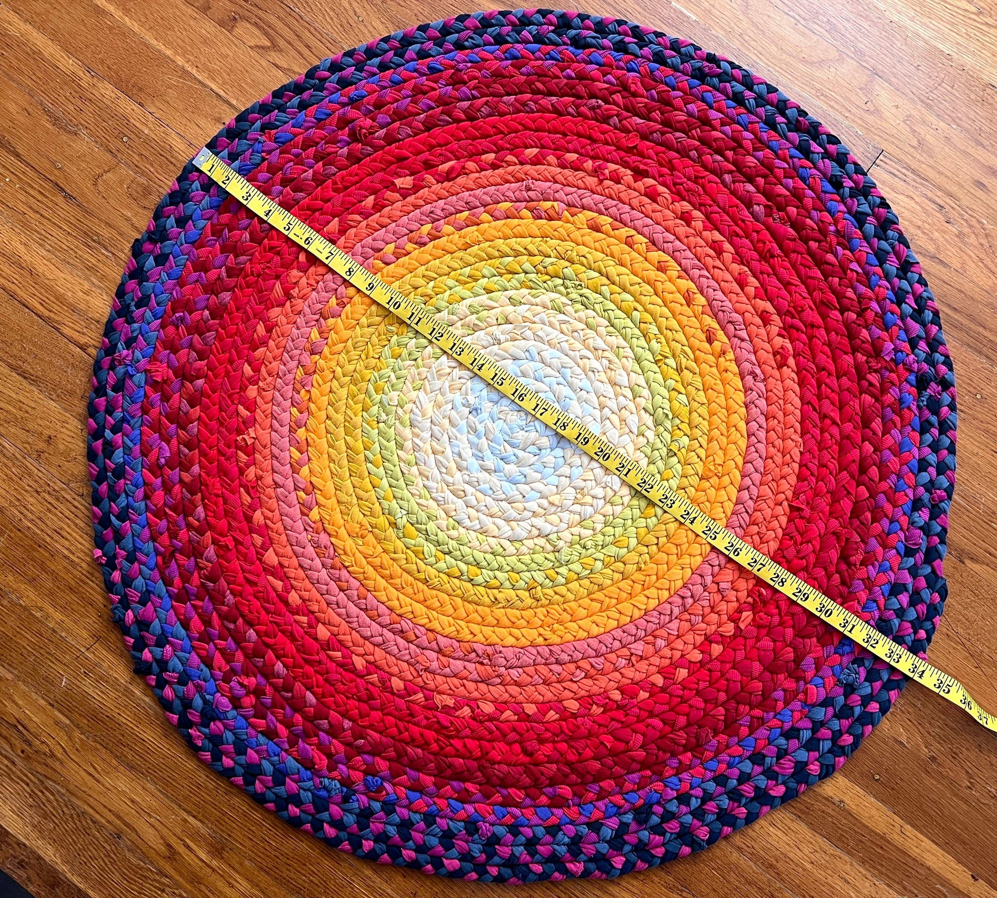 aerial view of the sunset ombré tshirt rug, with measuring tape across the top to show the diameter.