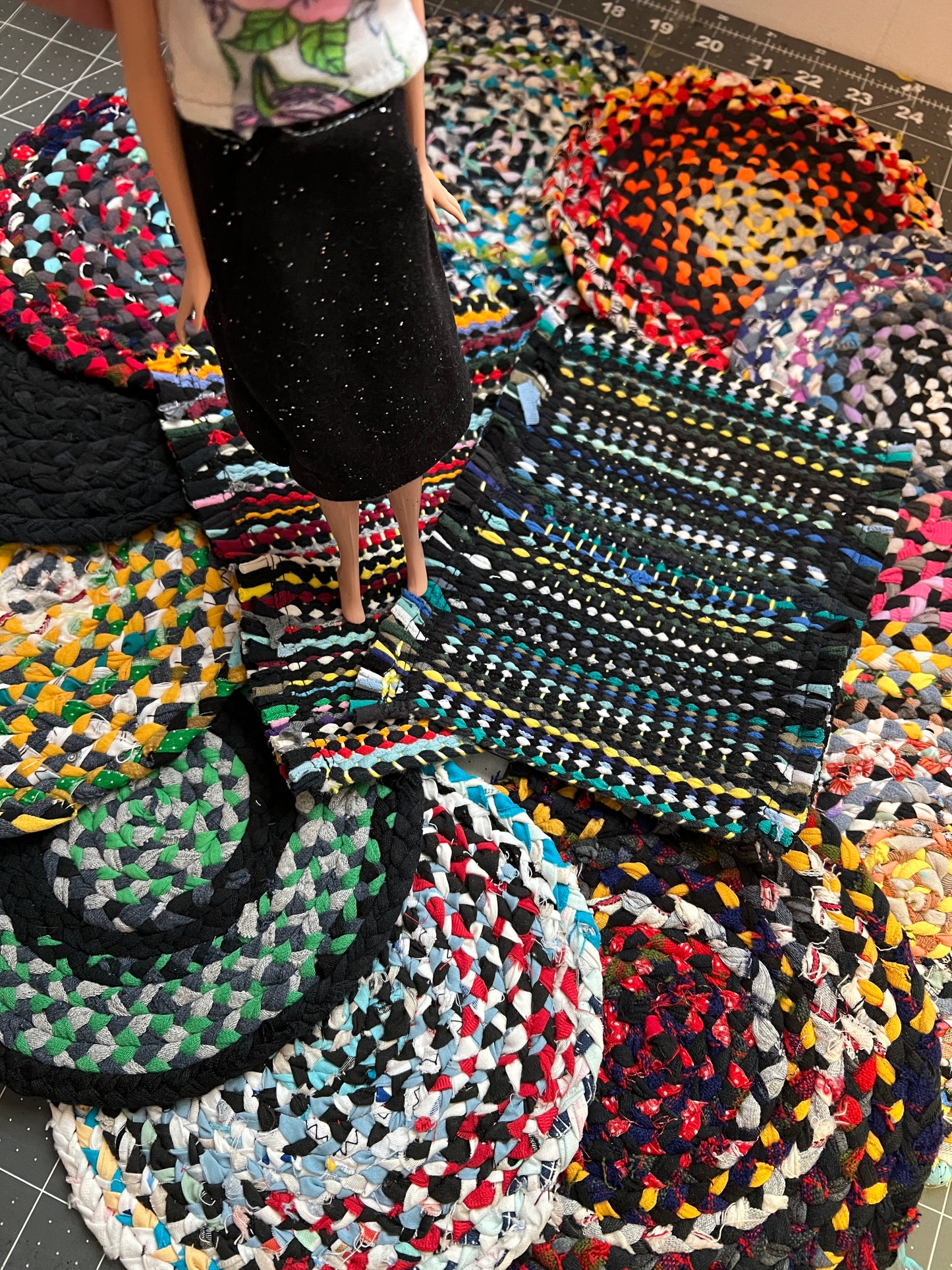 Barbie stands on top of various handbraided or woven rugs