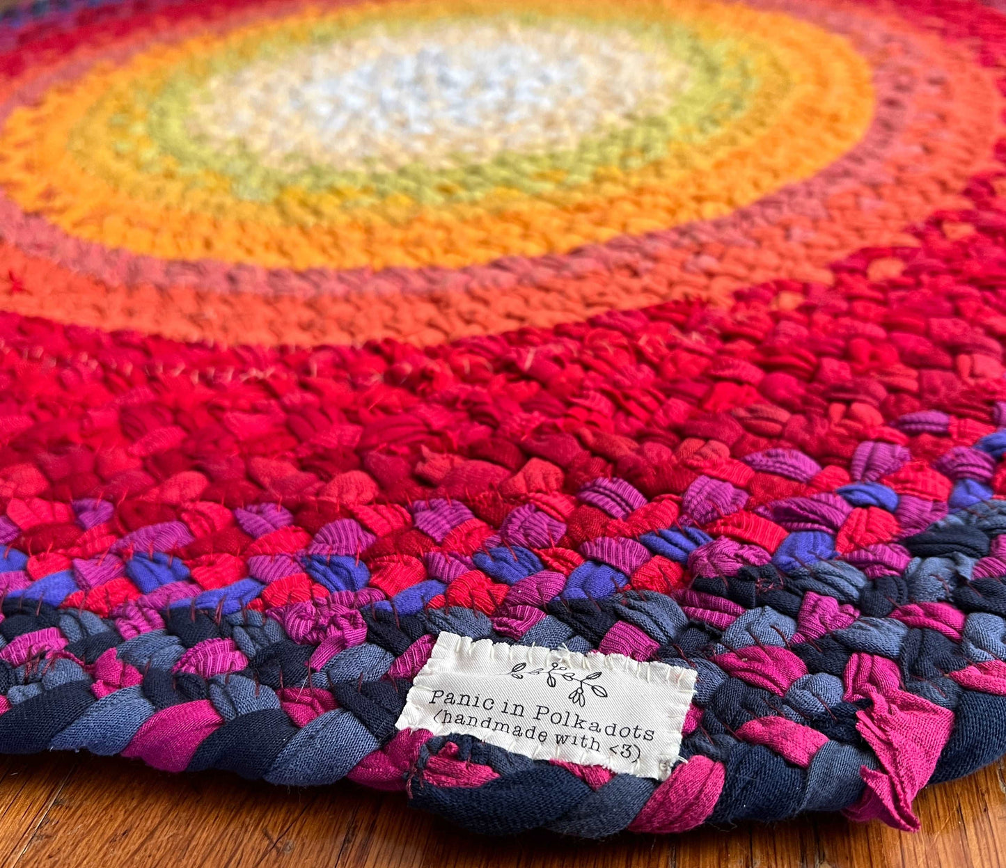 white yellow orange red pink and purple strip have been hand-braided and handsewn into this sunset rug