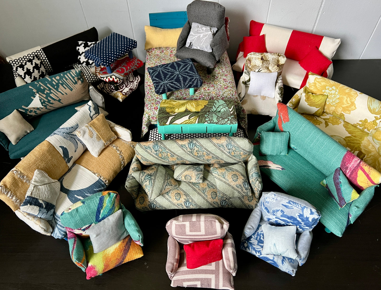 A group of miniature dollhouse couches, chairs, and ottomans,