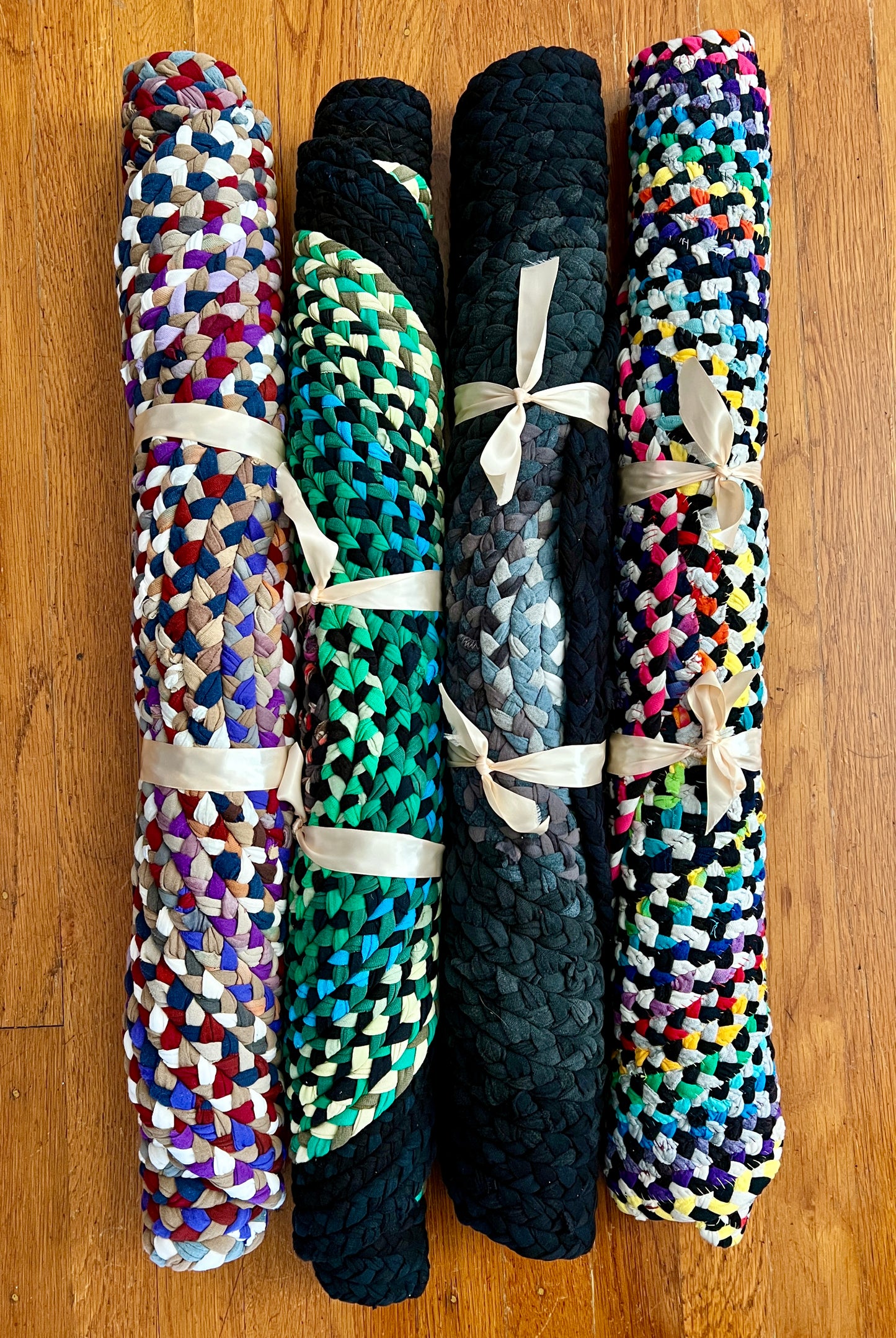 aerial view of a group of four rugs, rolled up and tied with ribbon, all laying side-by-side