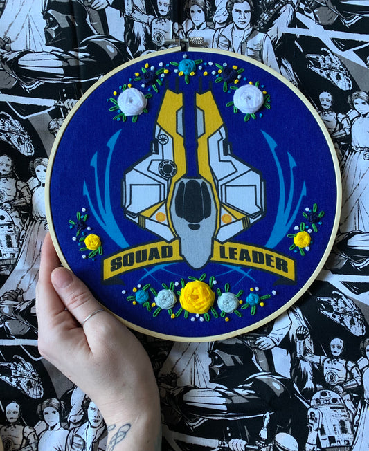 Star Wars Squad Leader embroidery hoop wall art, against a star wars fabric background. hand for scale