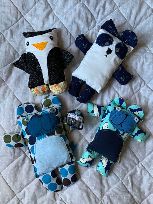 A group of extra cute plushie bears and a penguin, on a quilted grey background.