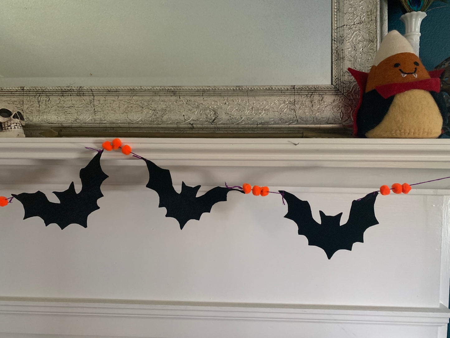a closeup of three of the bats on the garland. their silhouettes contrast against the white background of the fireplace mantle