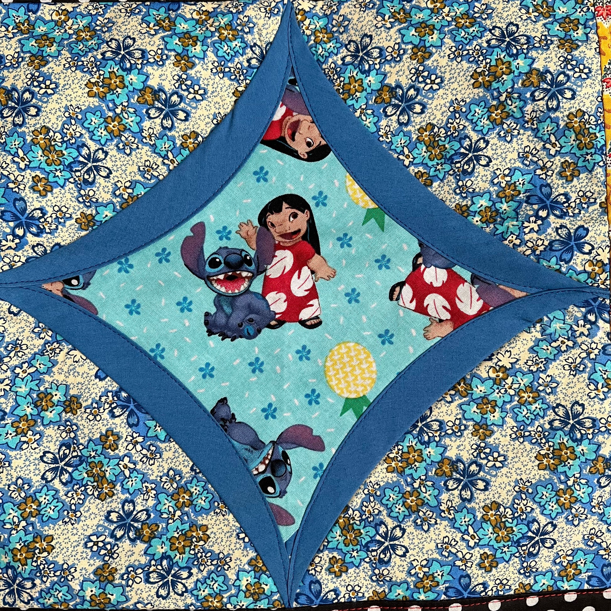 Lilo and Stitch fabric square, surrounded by blue and then blue floral fabrics