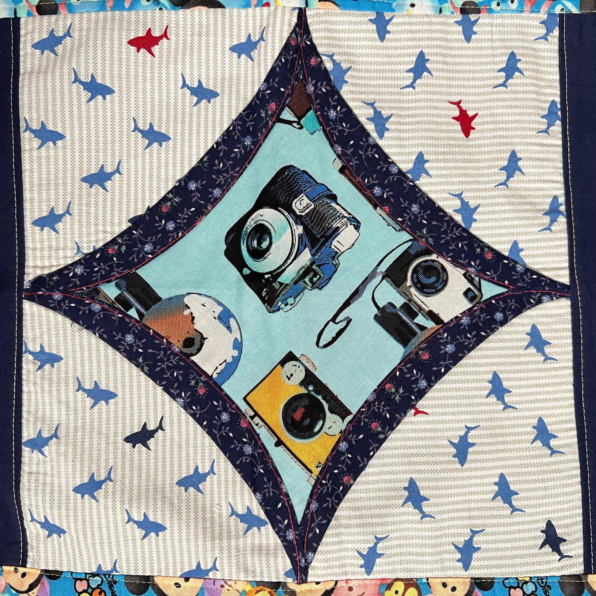vintage film camera fabric square, surrounded by dark navy florals and then shark print fabrics