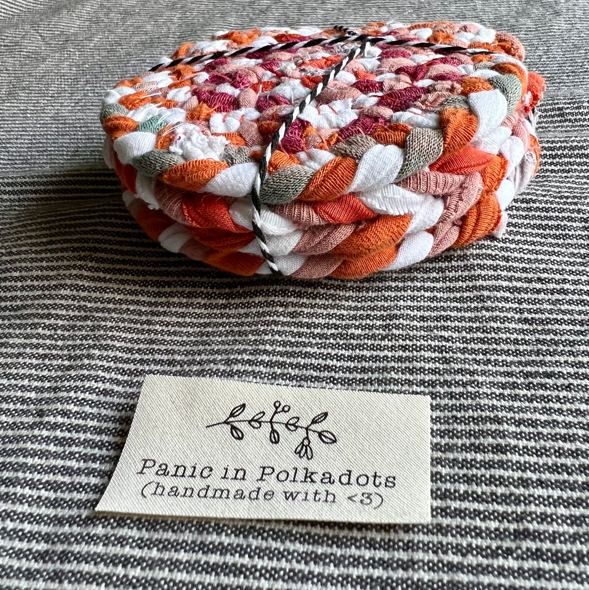 A set of four coasters, bound by string in a stack, with a Panic in Polkadots label in front