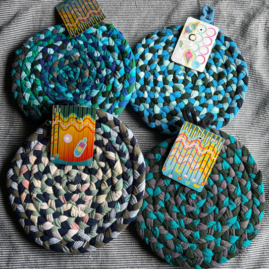 Four sets of trivet potholders, all laid together in a pile. Each set has a playing card with info about Panic in Polkadots.