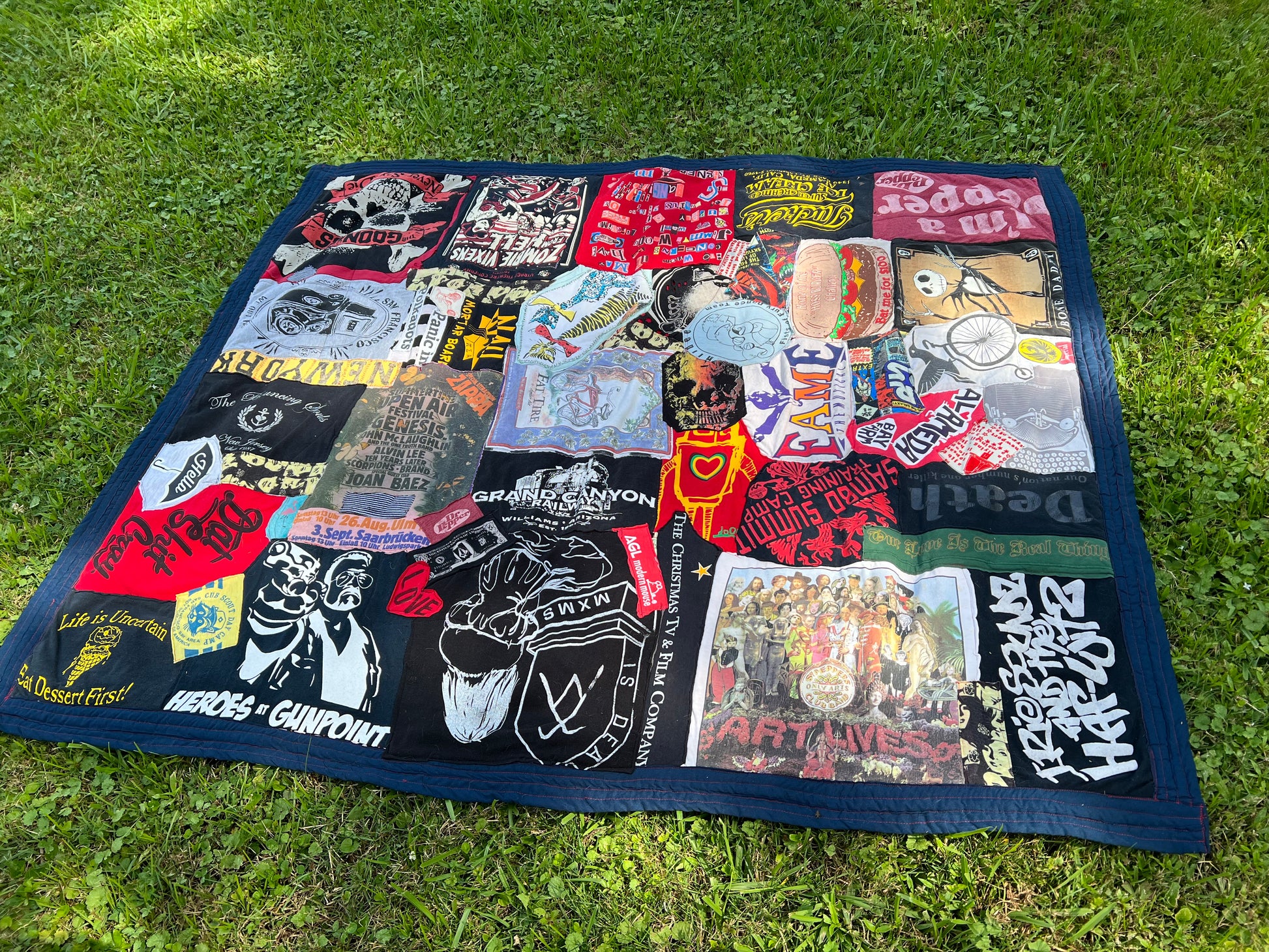 A collage-style tshirt quilt laid out on a nice patch of green grass