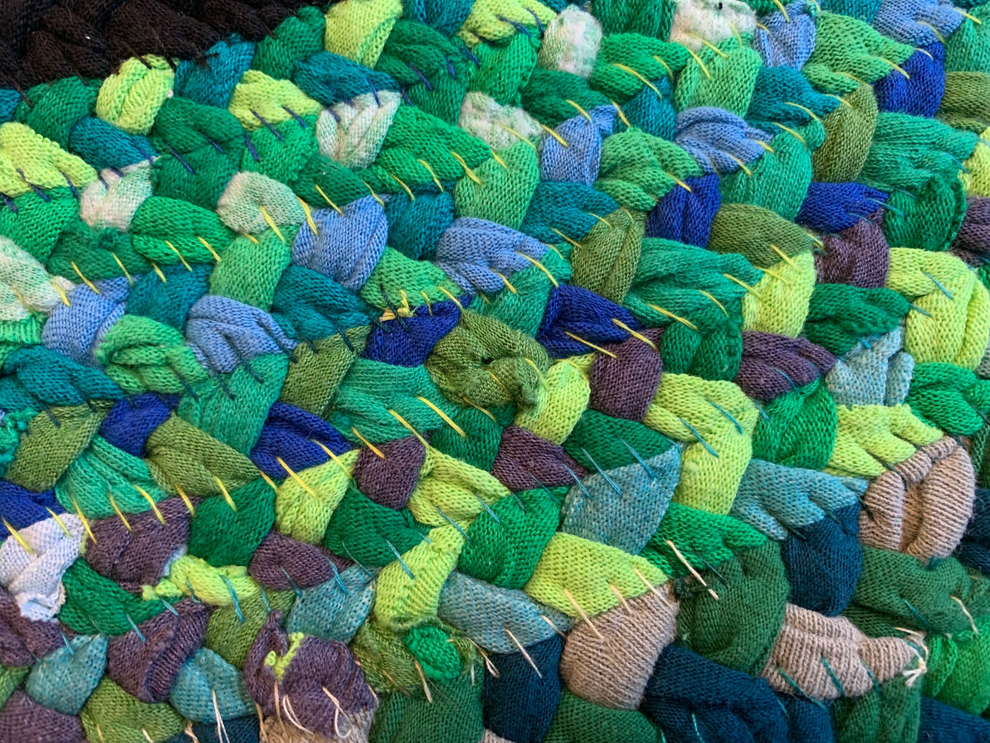 closeup of the back side of the quilt, with contrasting varied green stitching