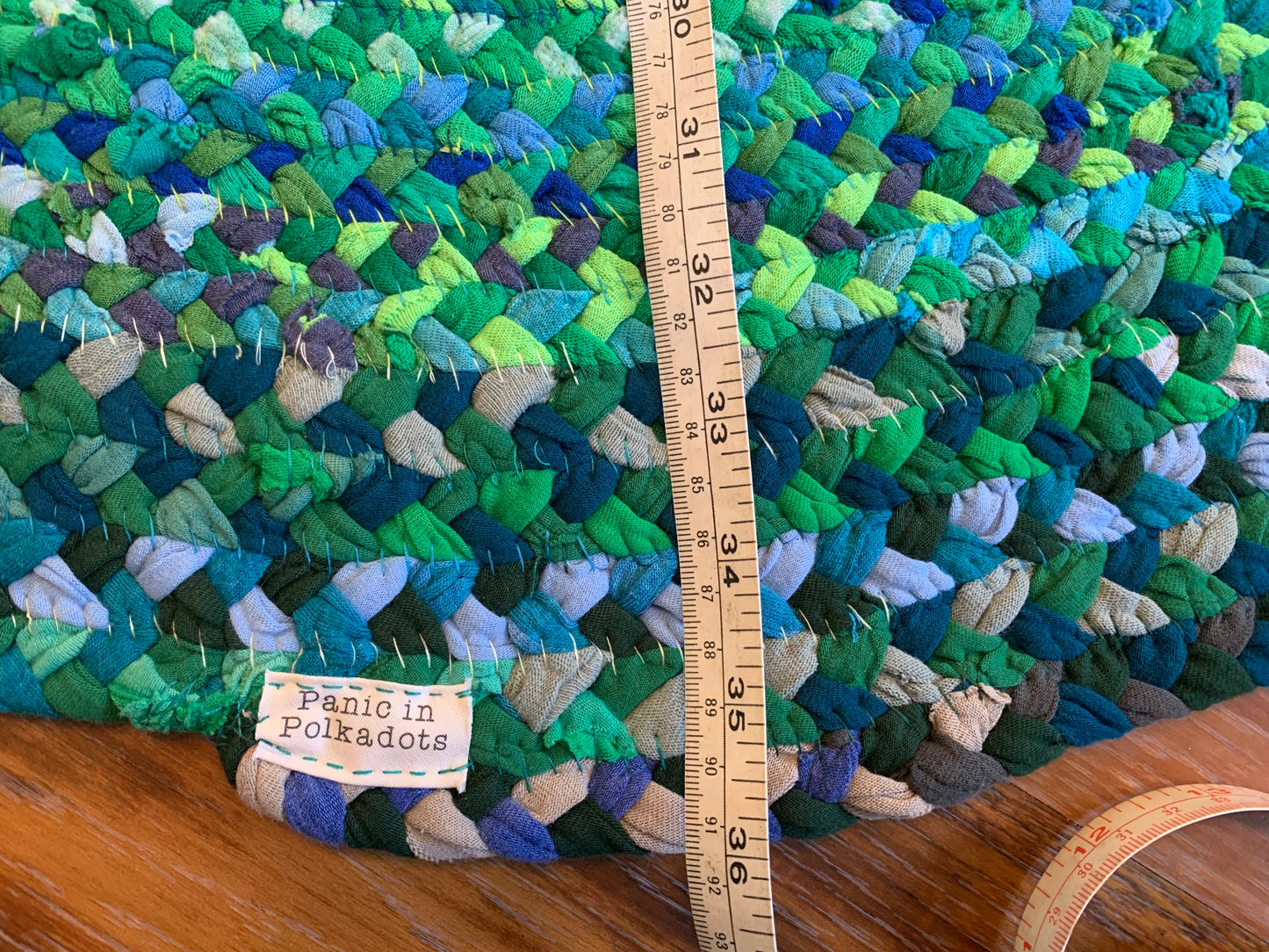 back side of rug, with hand stitching, and a measuring tape closeup, showing 36 inches as the diameter.