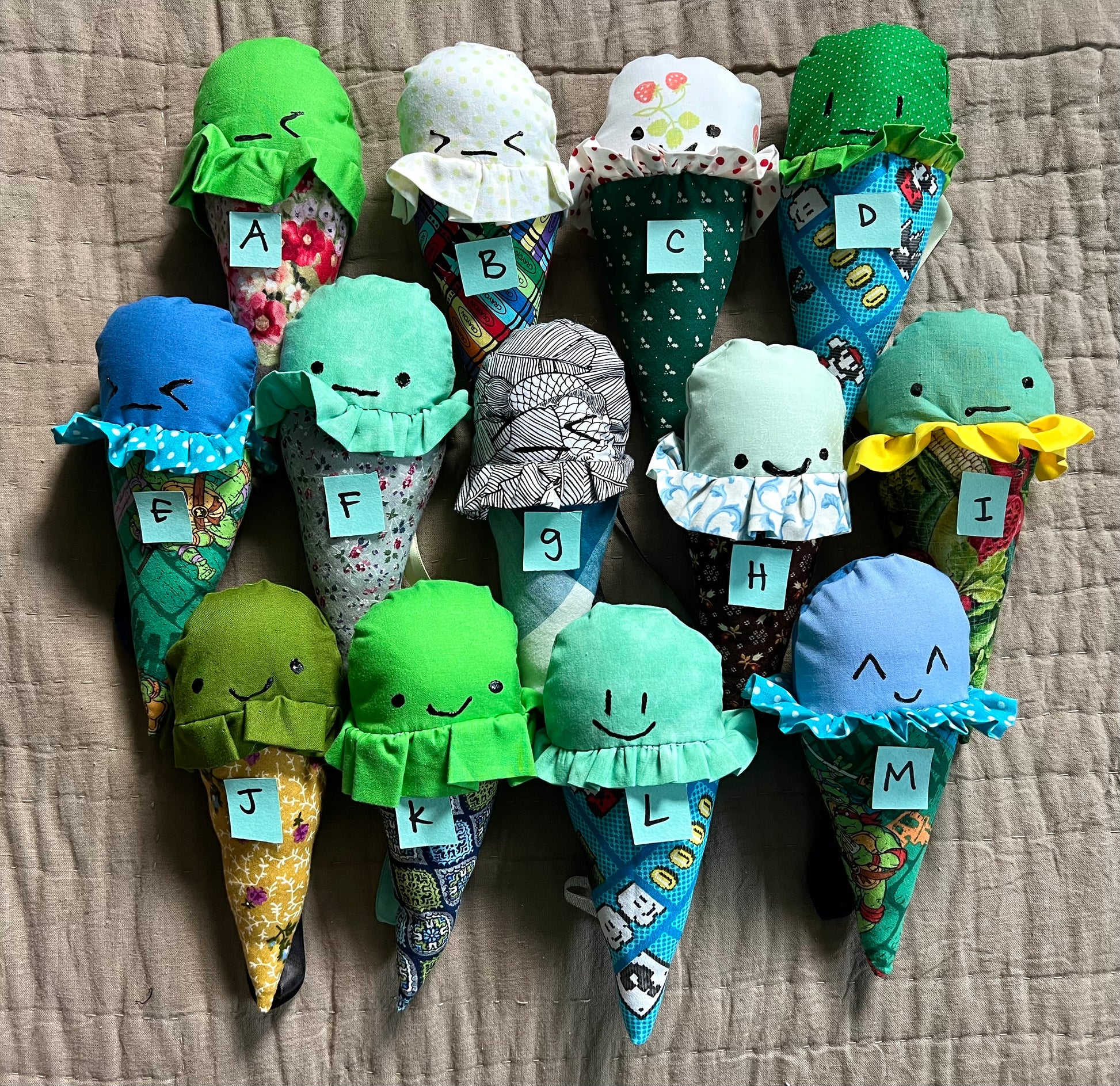 A group of colorful ice cream cone plushies, all lined up next to each other with coordinating letters on top of each one for easy selection.