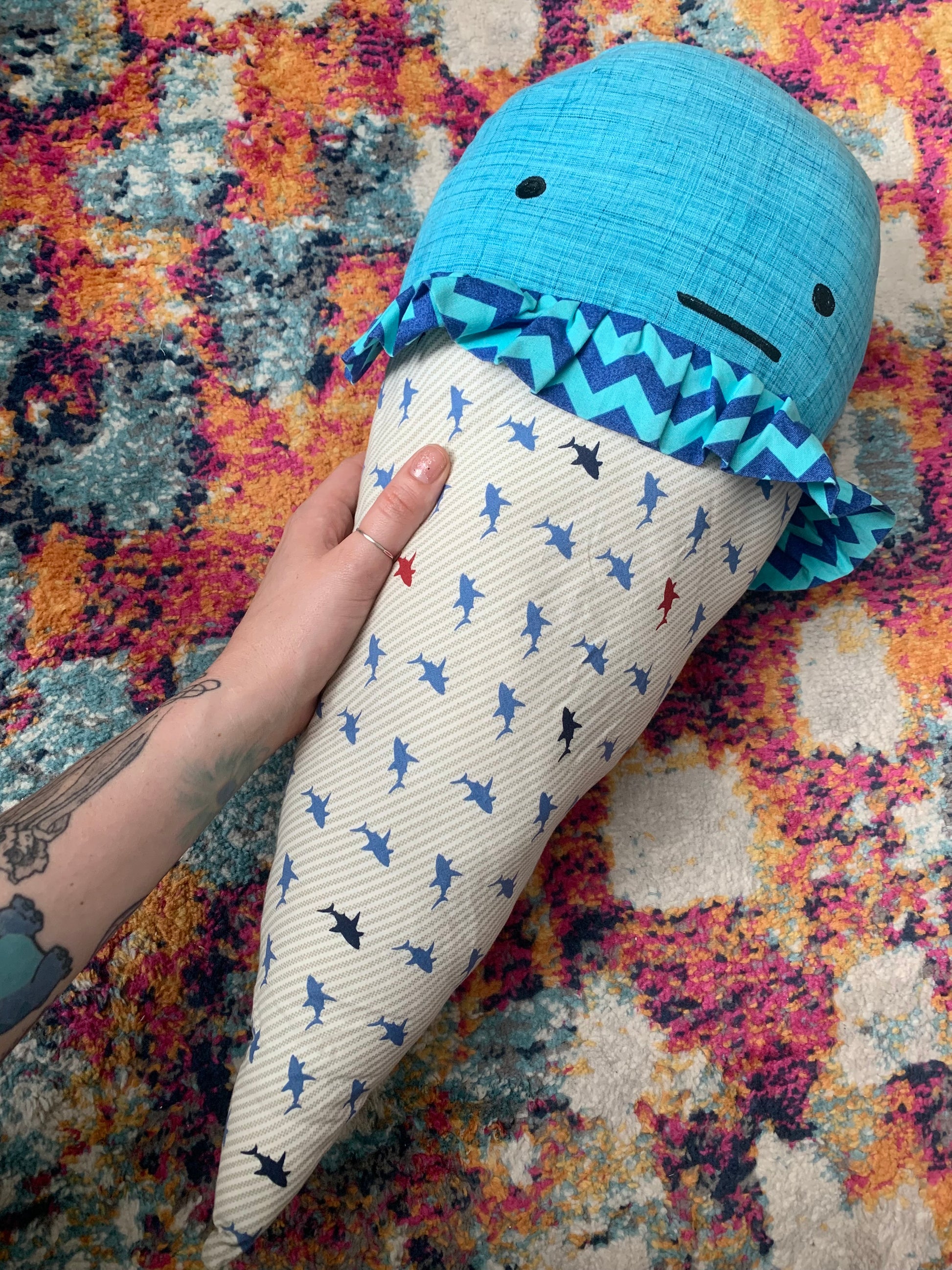 GIANT ice cream cone pillow, with blue ice cream top, an indifferent face, and a shark print cone fabric, held by a hand to the side, for scale