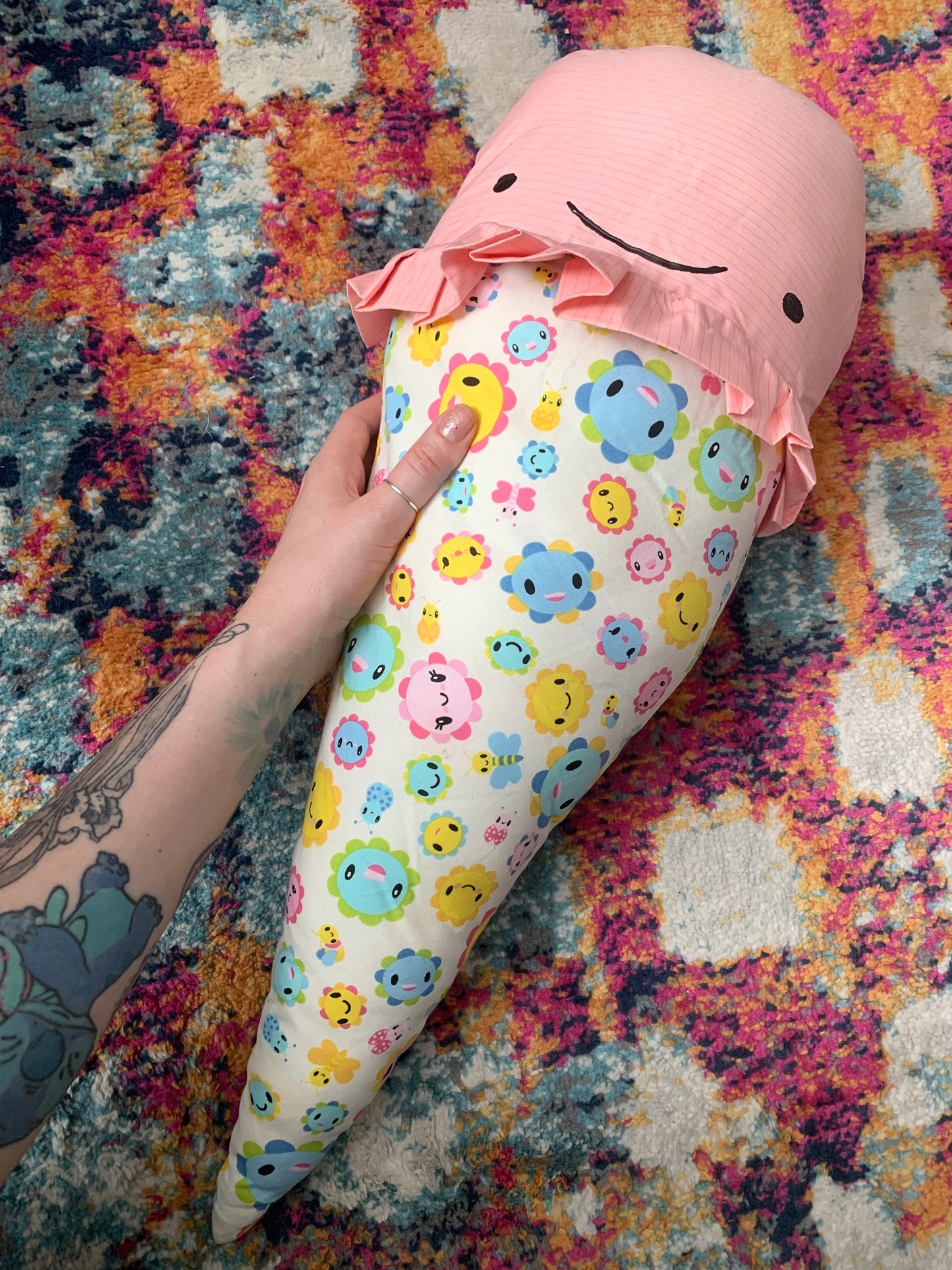 GIANT ice cream cone pillow, with Pink Strawberry ice cream top, a happy face, and colorful flower happy faces allover print fabric cone, held by a hand for scale
