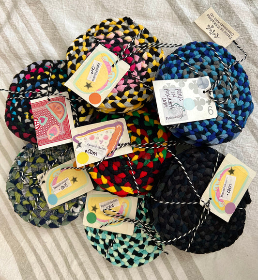 A pile of mini rug coaster bundles, aerial view. Each set is bound by string and a Panic in Polkadots tag
