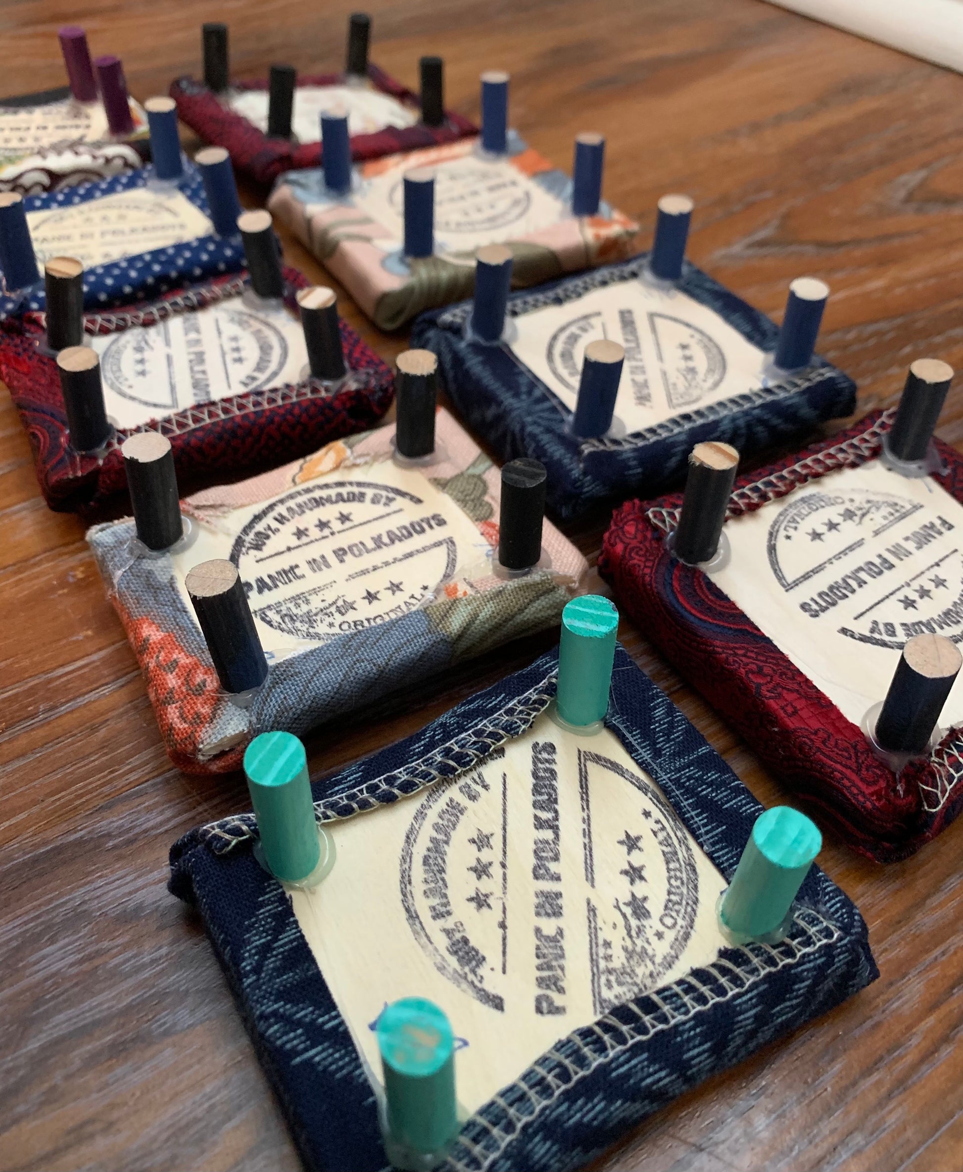 aerial side view of various miniature ottomans, showing the underside where a "100% handmade by Panic in Polkadots" stamp has been added to the wood base