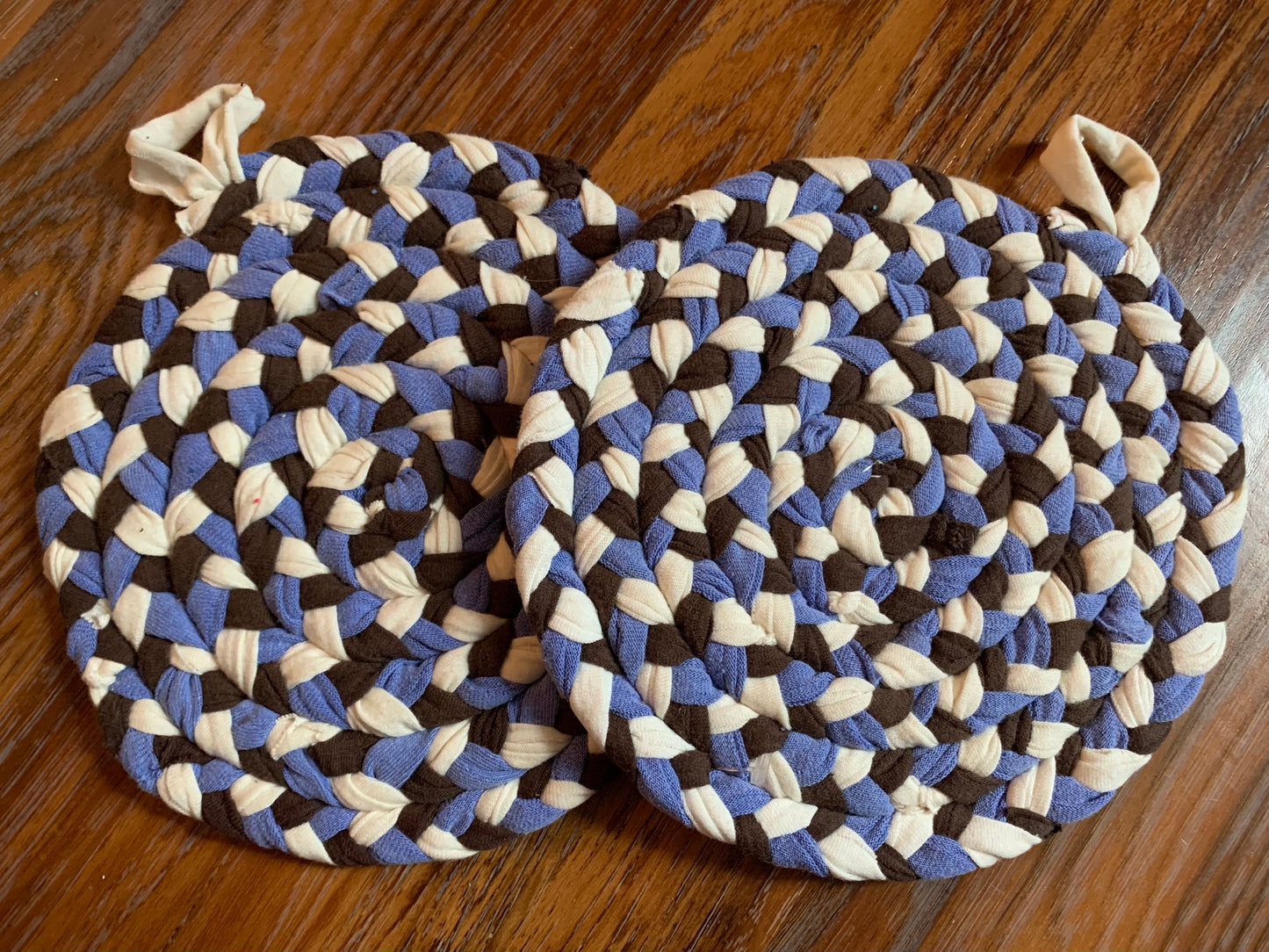 A set of two trivet potholders, side by side, lay flat on a wood surface.