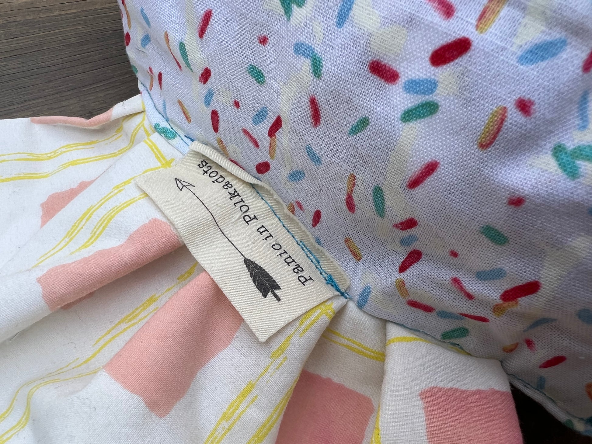 "Panic in Polkadots" label, closeup view, as it is shown sewn into the "wrap" part of candy pillow