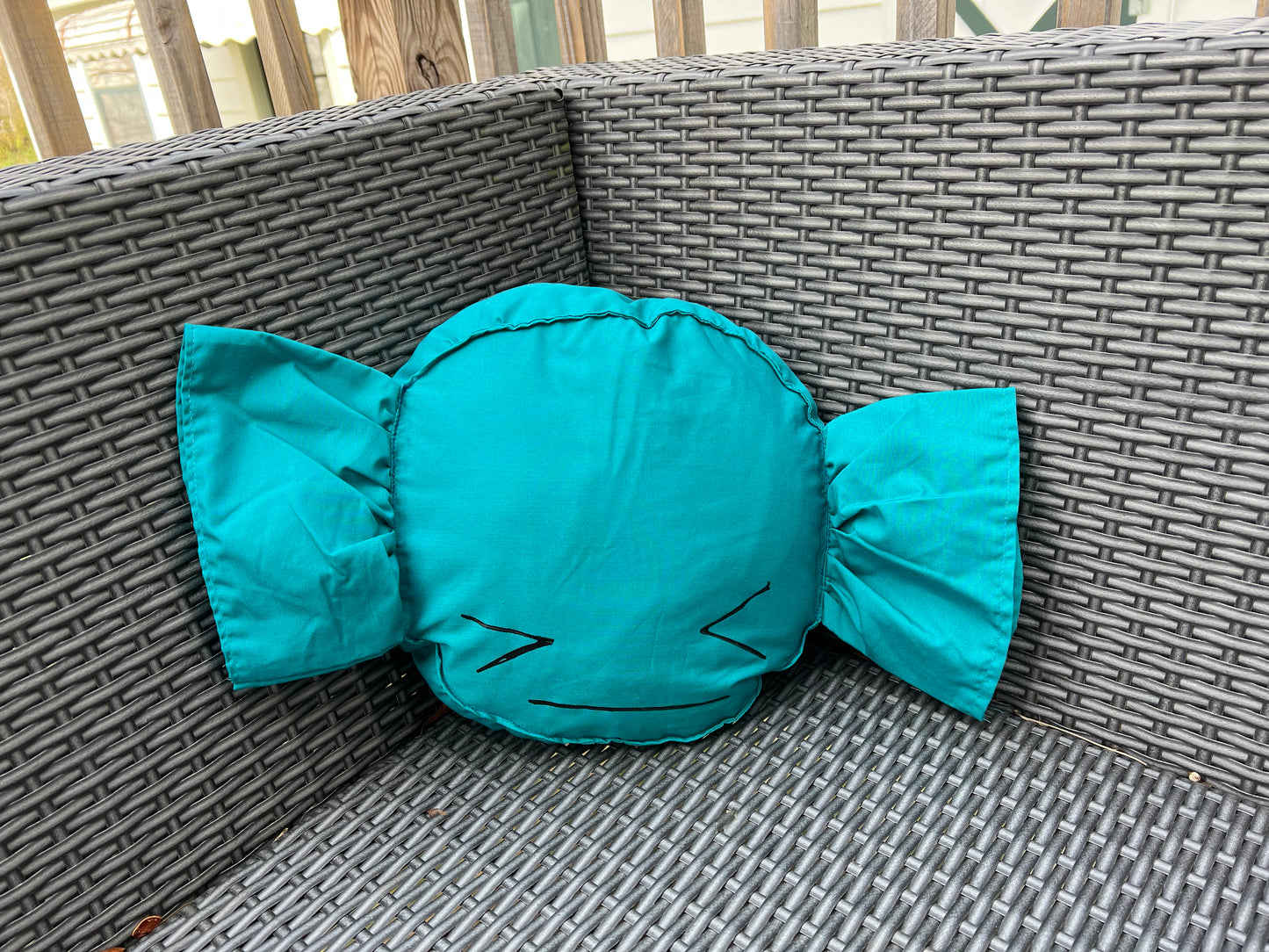 cute candy pillow, nestled in the corner of an outdoor patio chair.