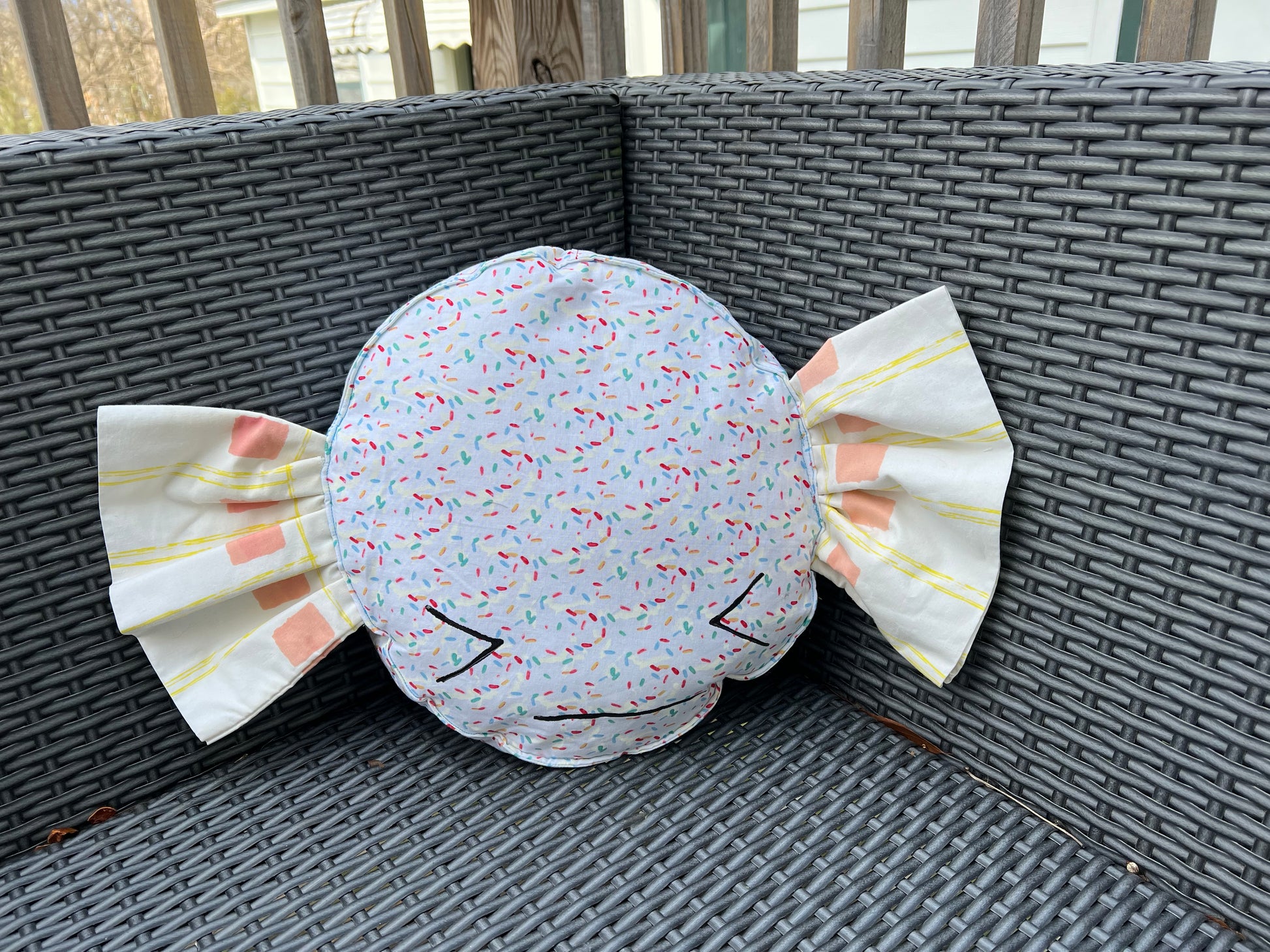 cute candy pillow, nestled in the corner of an outdoor patio chair.