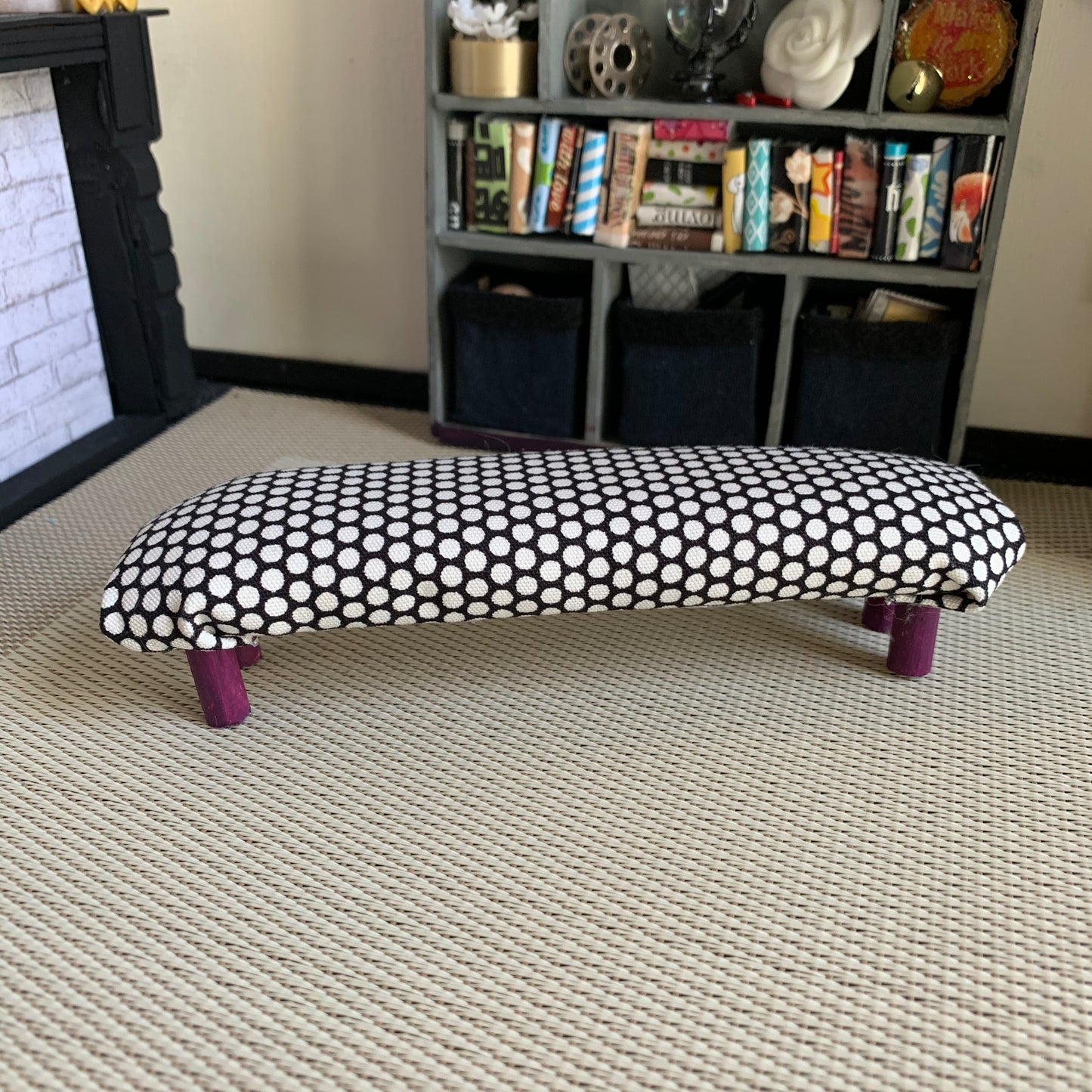 a miniature dollhouse bench, in a dollhouse room for scale. This one is black with white polkadots, with dark purple legs