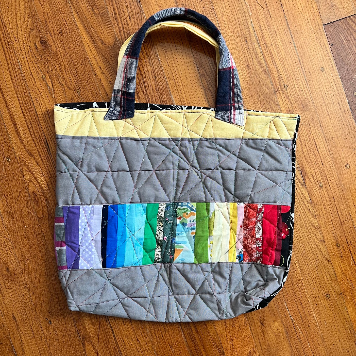 aerial view of rainbow stripe quilted tote bag against a wood background
