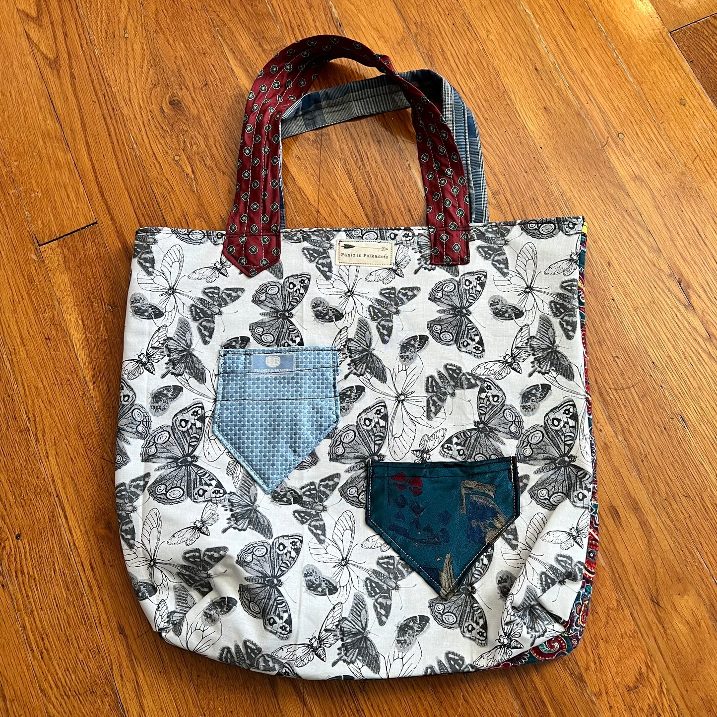 back view of tote bag, with two small necktie pockets and a Panic in Polkadots label