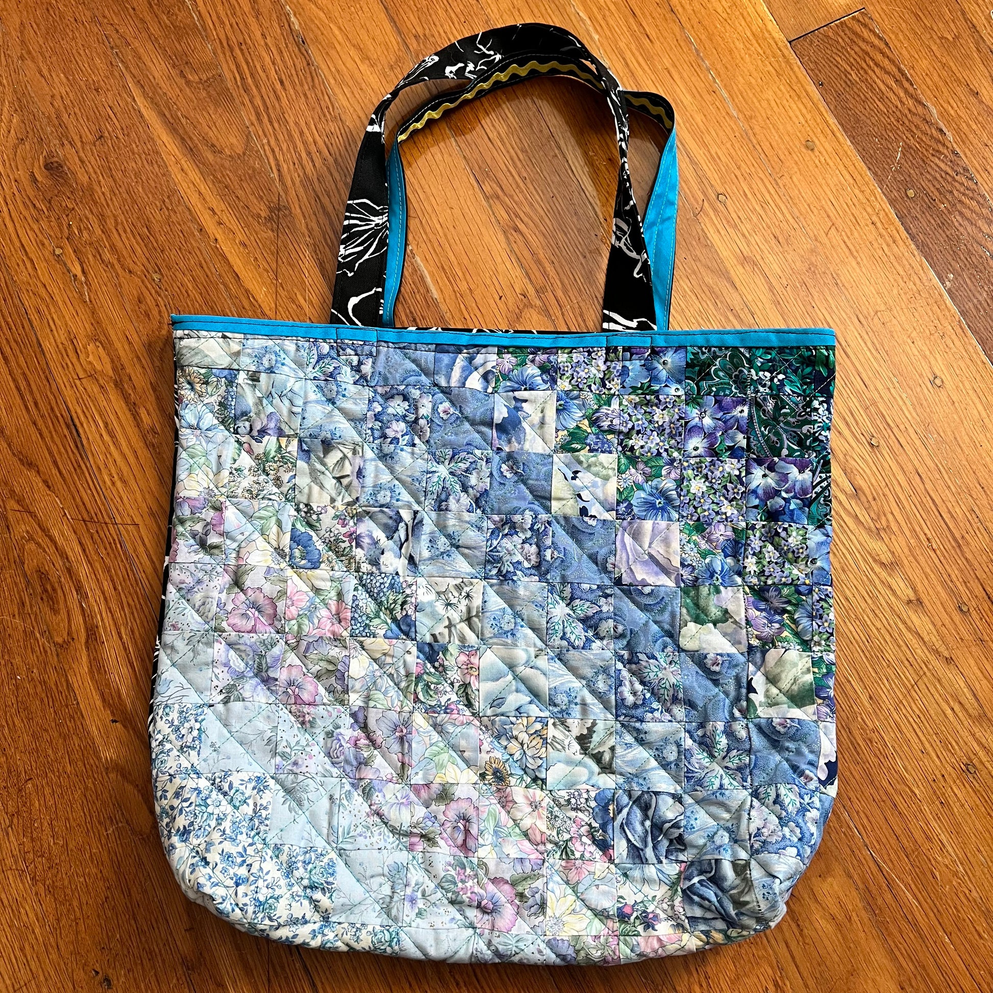 aerial view of quilt square ombré quilted tote bag against a wood background