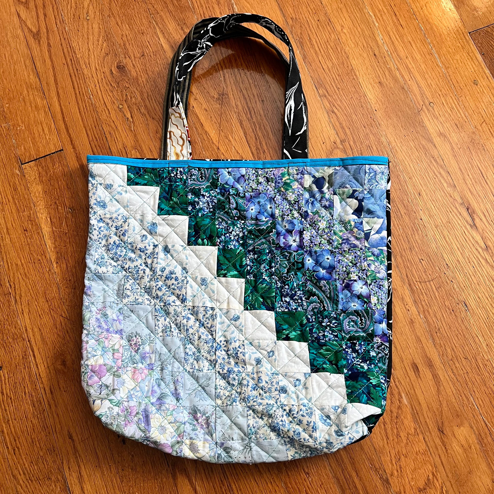 aerial view of quilt square ombré quilted tote bag against a wood background