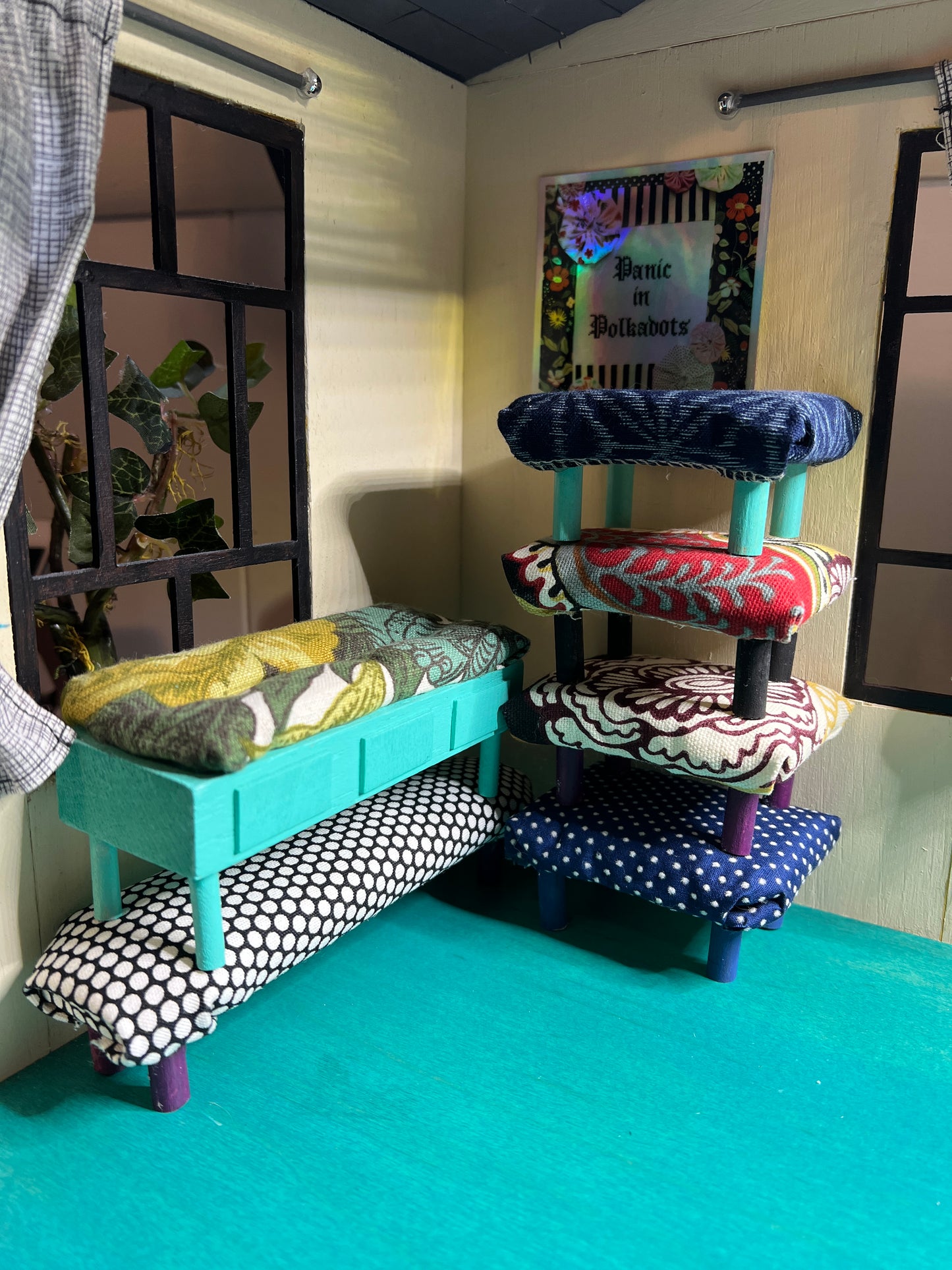 stacked dollhouse ottomans and benches, in a miniature room, with windows and a Panic in Polkadots sticker on the wall