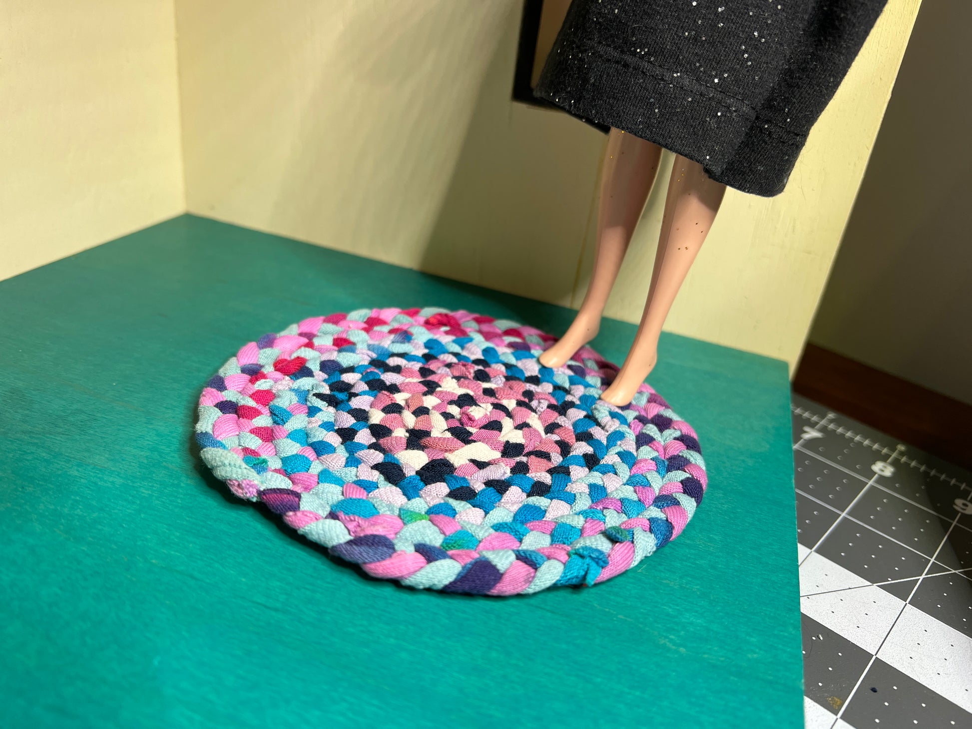 view of miniature rug in a room box, with Barbie standing atop the autumn colors rug for scale and display ideas