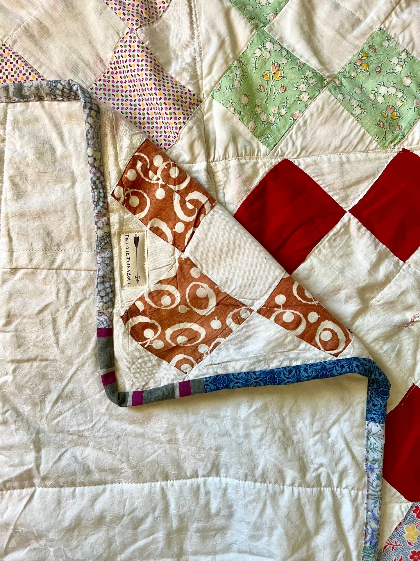 A vintage reconstructed quilt, folded a few times, with the corner folded over the backing and then the backing folded over the front