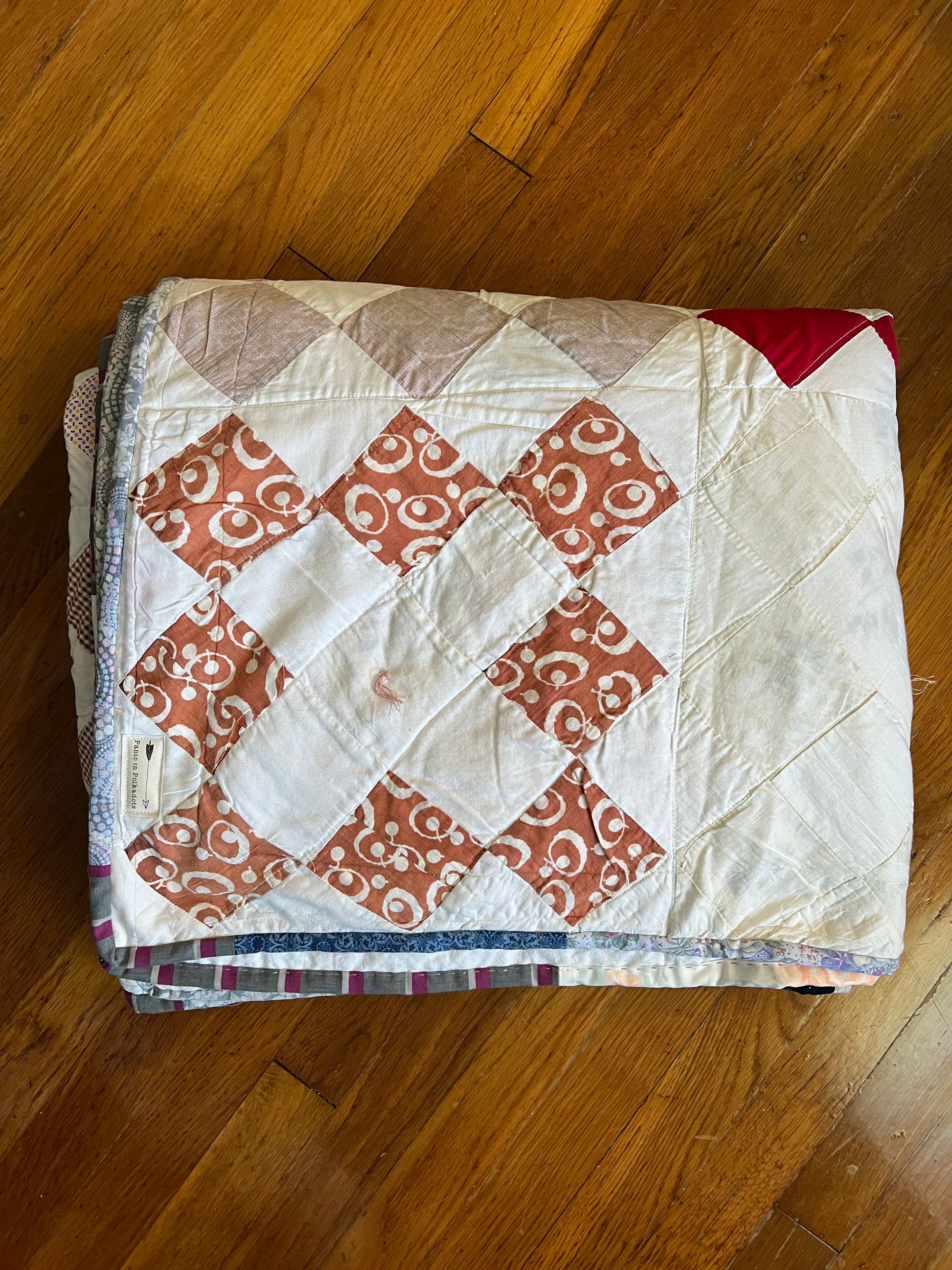 the quilt is folded neatly, and lays on top of a wood floor