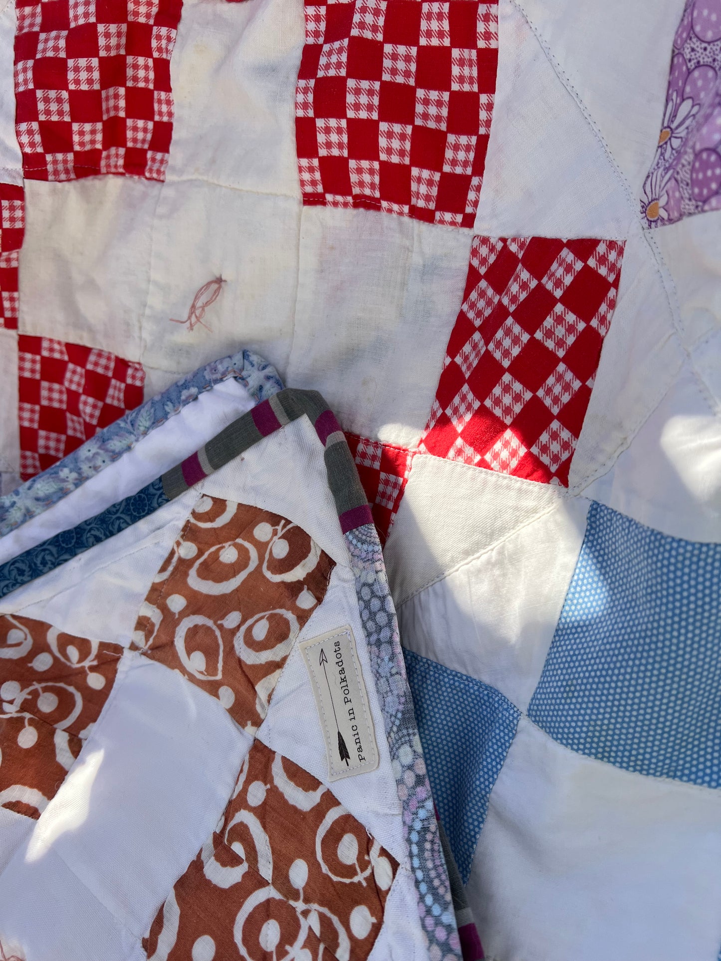 Splotches of sunshine kiss this vintage quilt, and a few corners are folded over into the middle