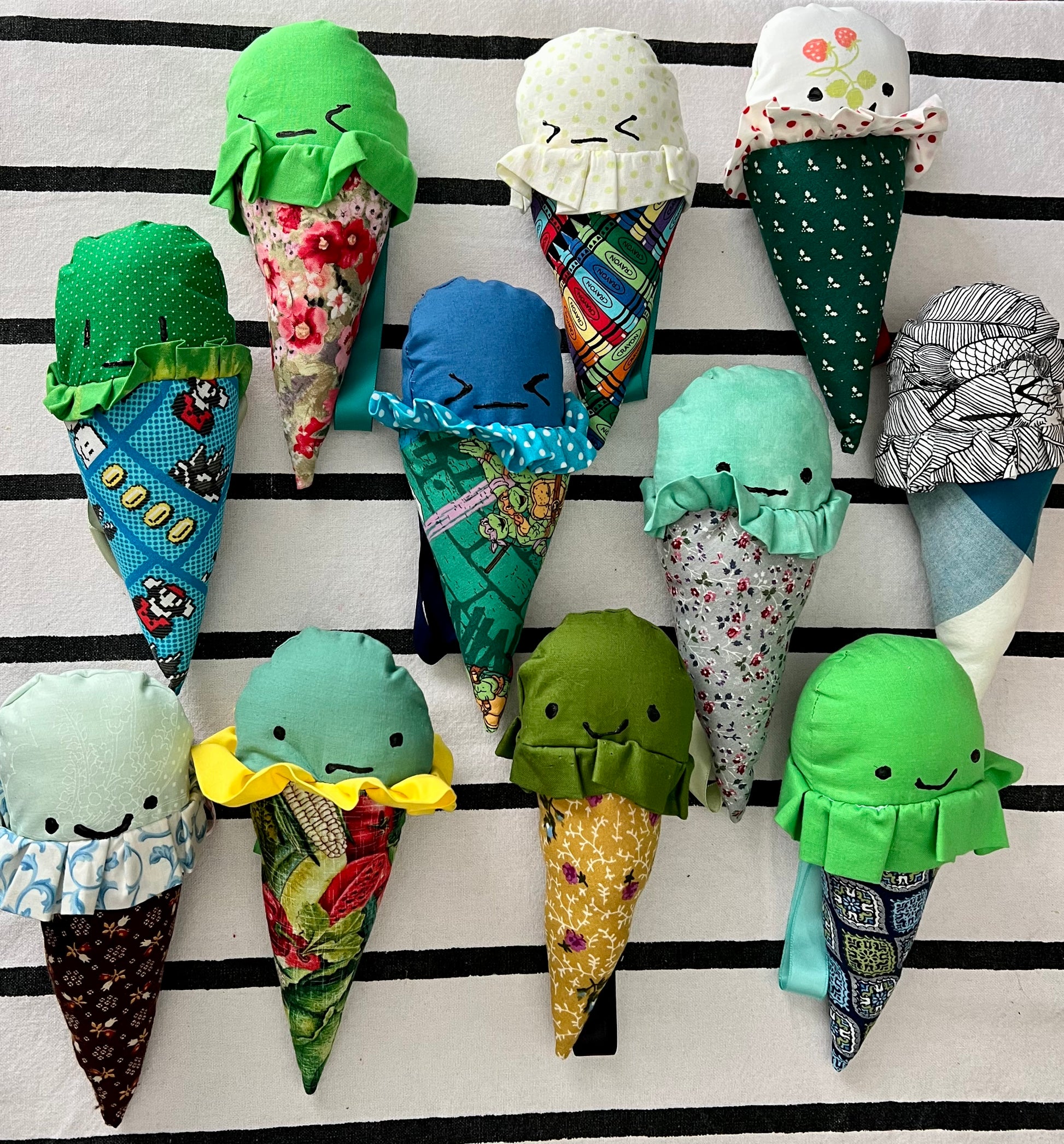 a group of green themed ice crem cones with handpainted faces against a striped background