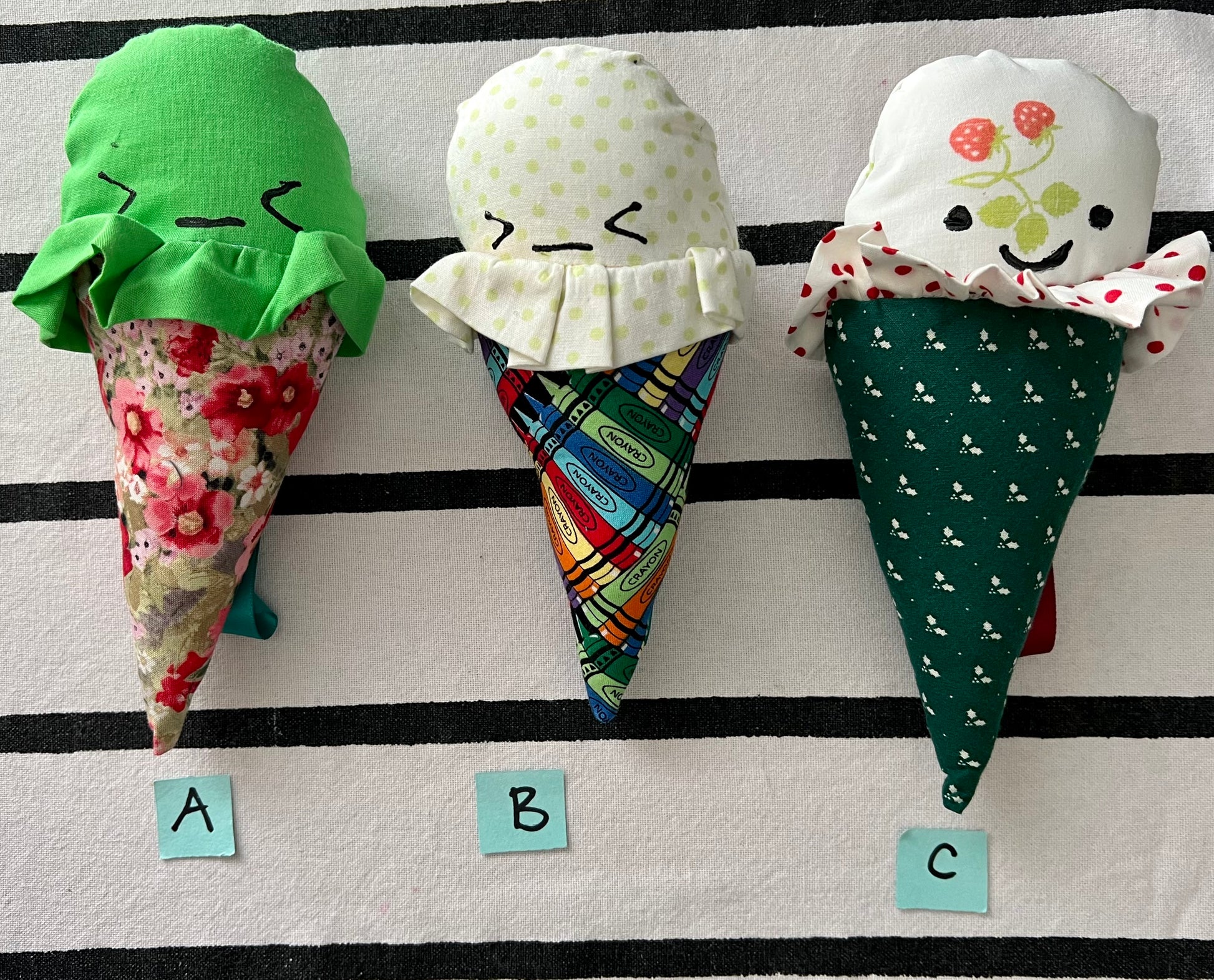 Ice cream cone plushies with handpainted faces, lined up with the letters A B C below them