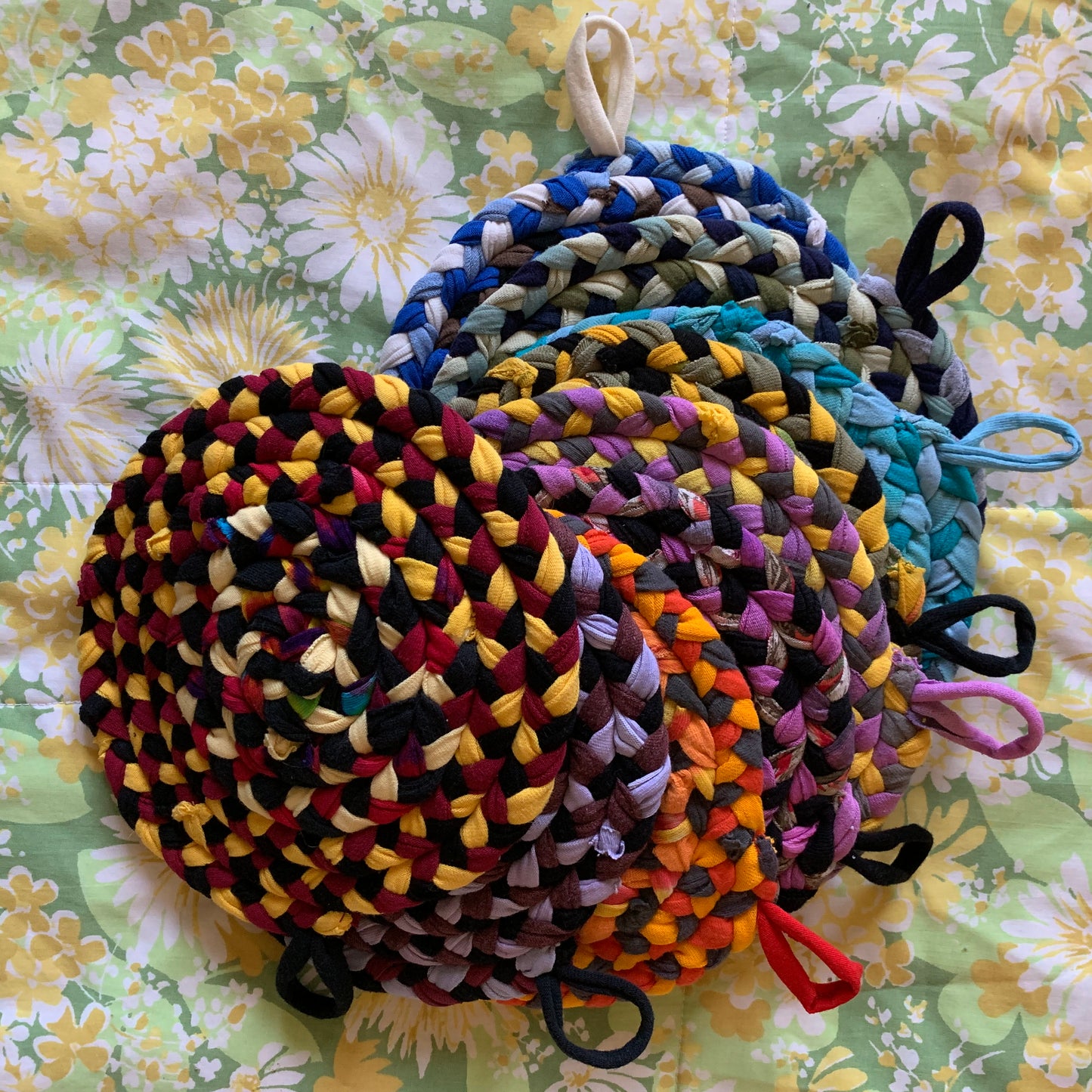 A group of trivet potholders, in a spectrum of colors, lay flat in a semi-spiral.