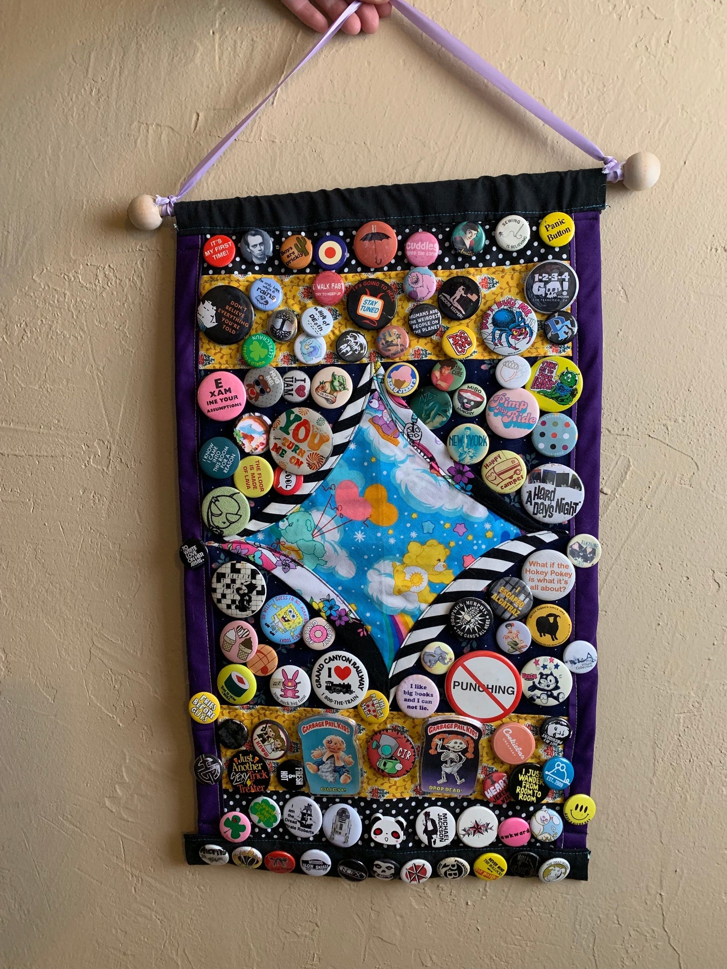 a pin display held against a wall, with various pinback buttons, to show ideas for collection display.