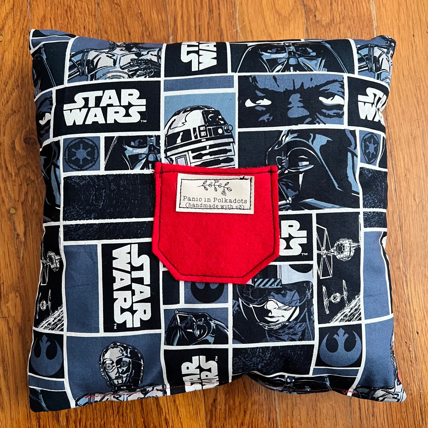 back view of pillow, with star wars print, and a felt red pocket with Panic label