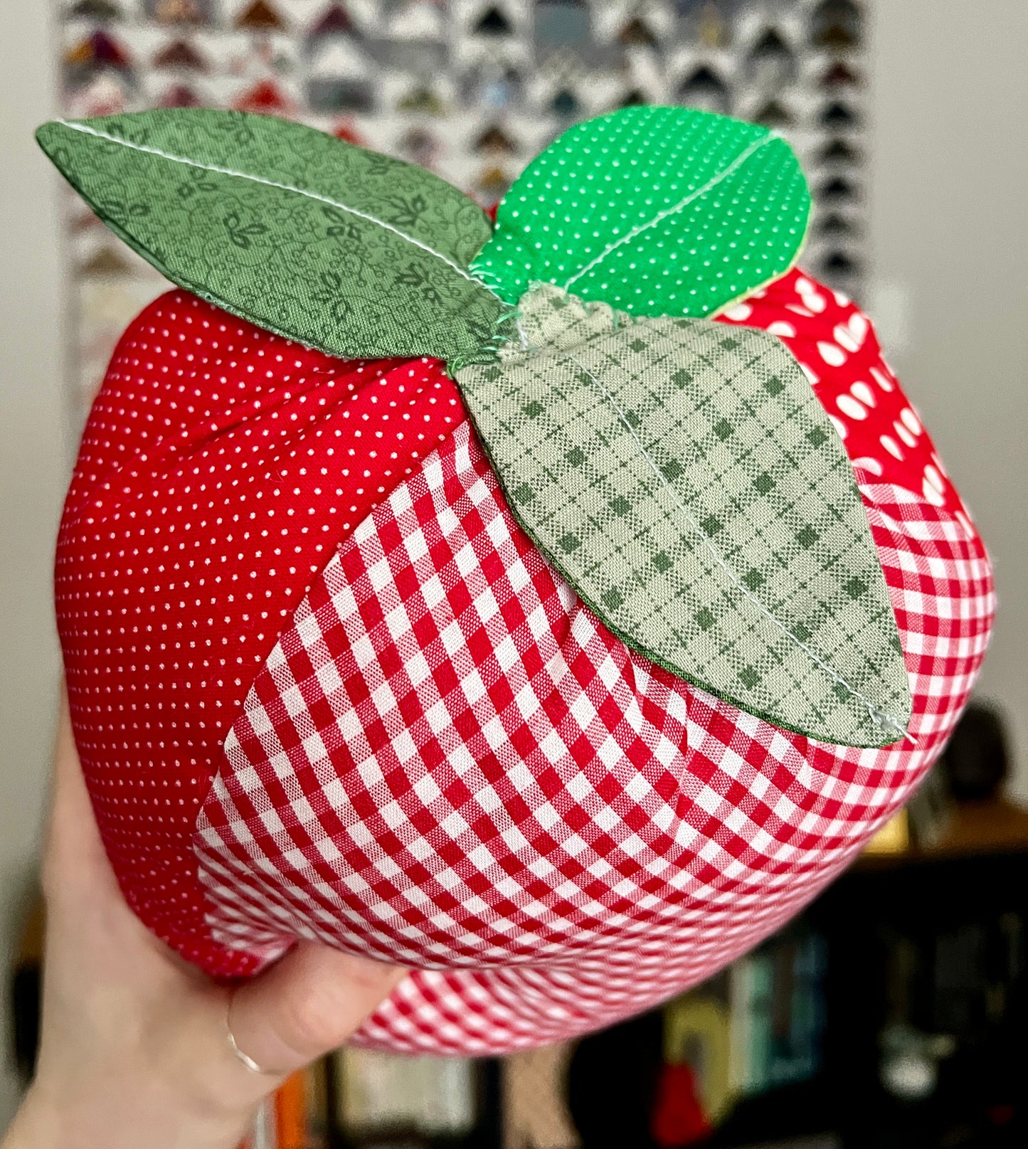 Strawberry shaped pillow, held up in hand for scale