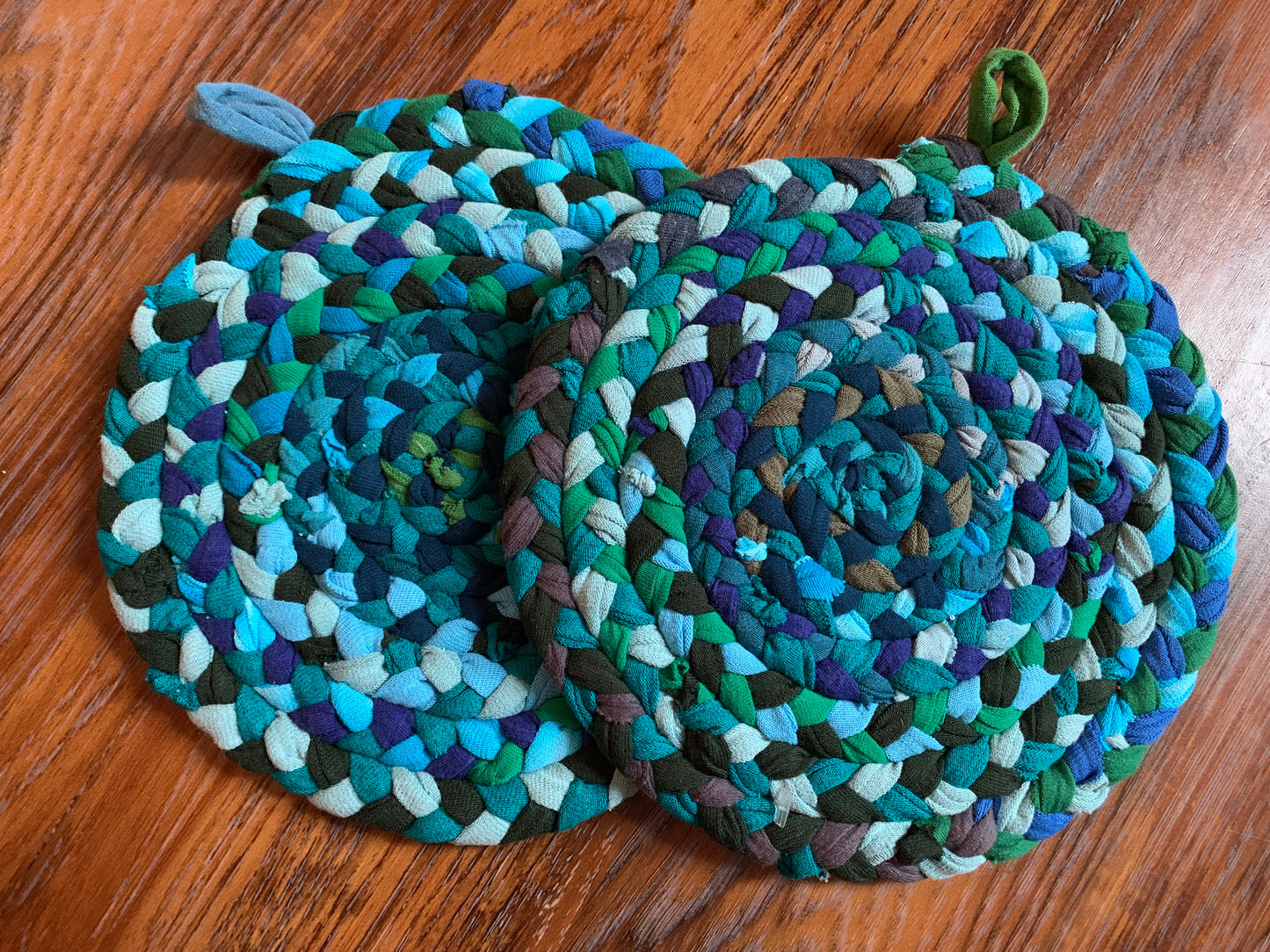 hand braided and hand sewn potholder/trivets set flat lay against a wood background