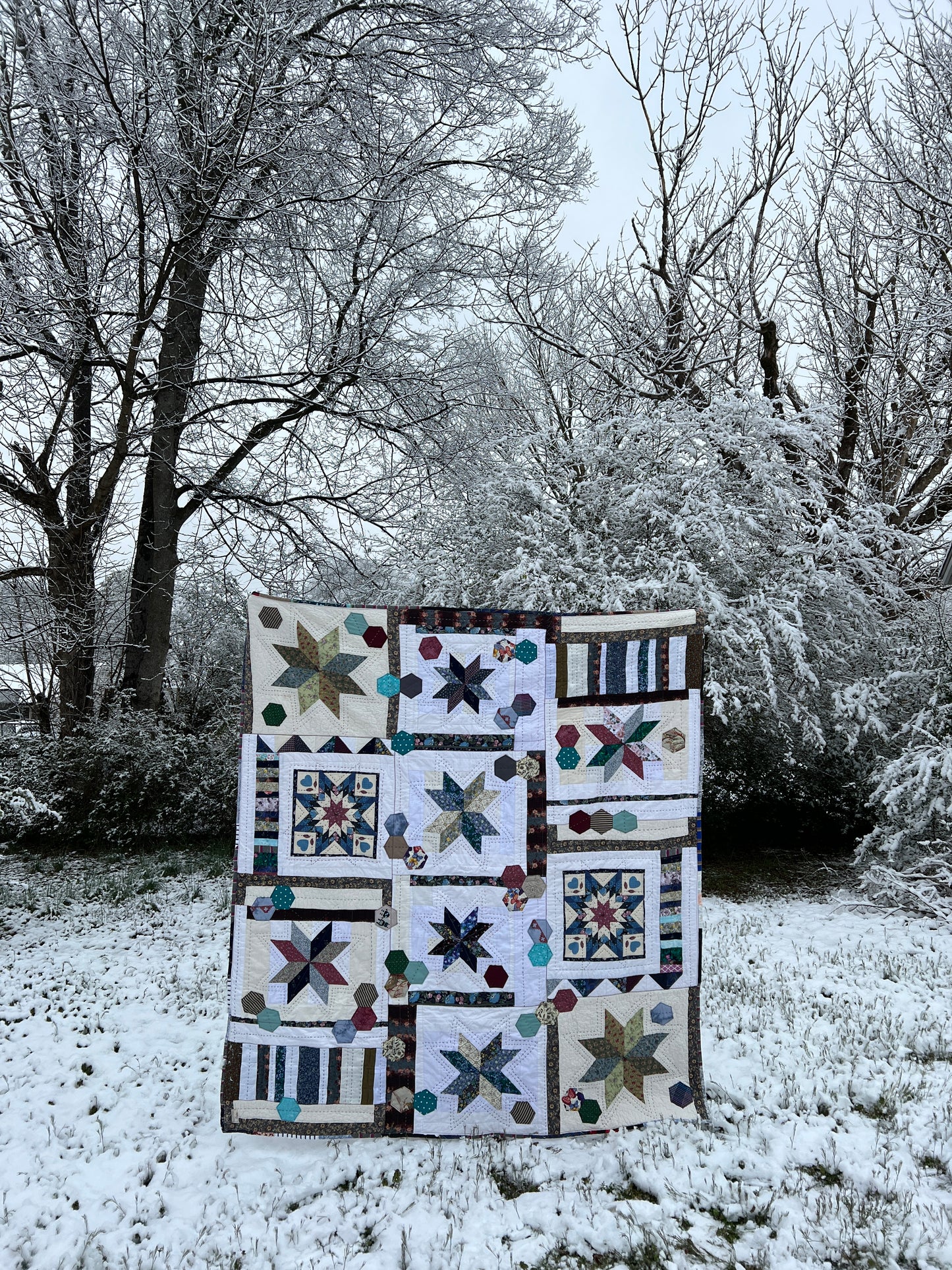 A quilt with eight point stars and quilted hexies, In a snowy outdoor scene