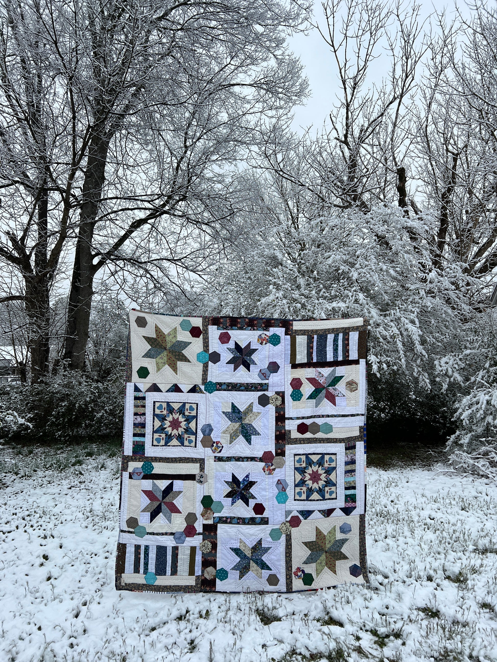 A quilt with eight point stars and quilted hexies, In a snowy outdoor scene