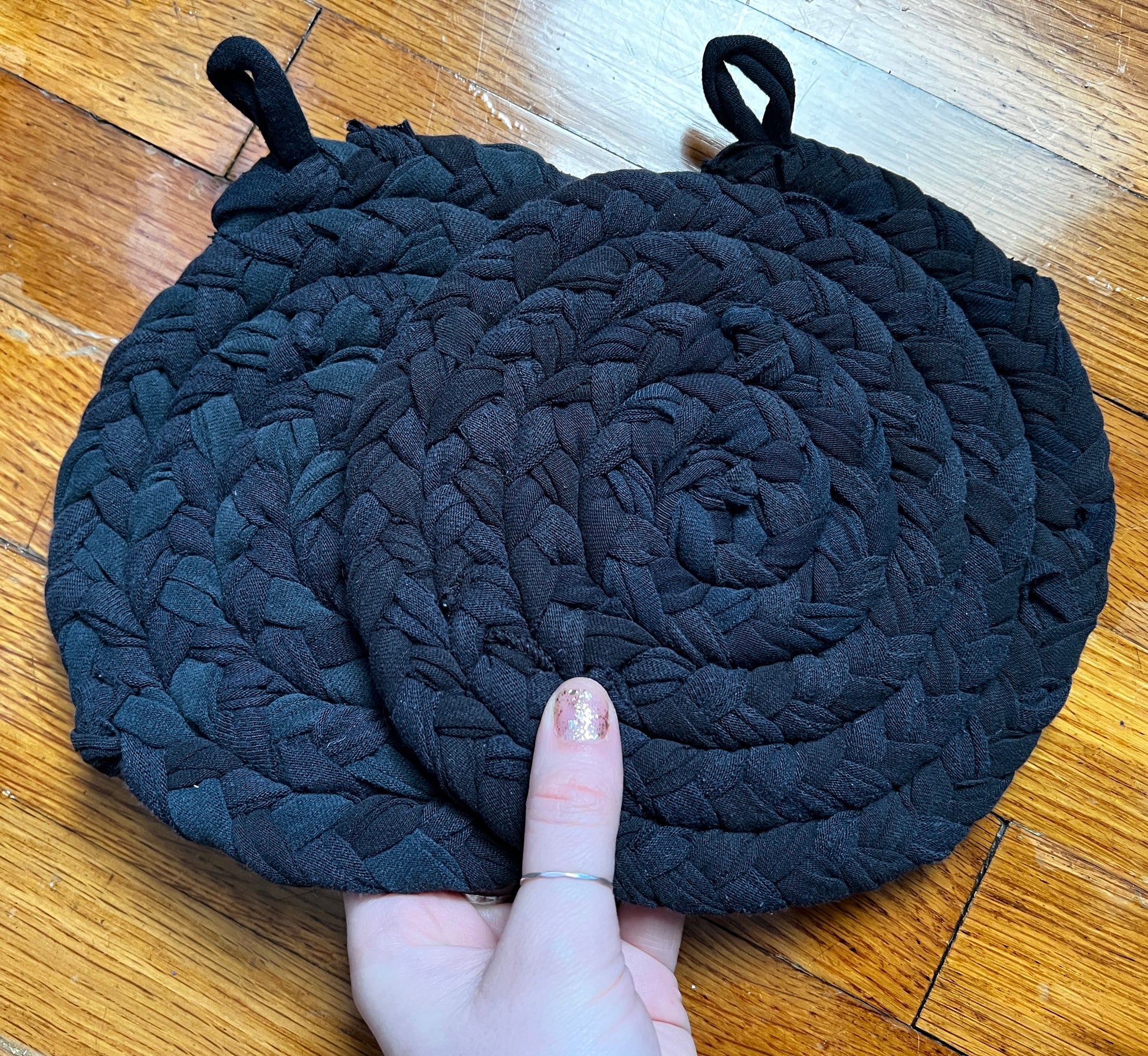 All Black potholders in hand for scale, against a wood background