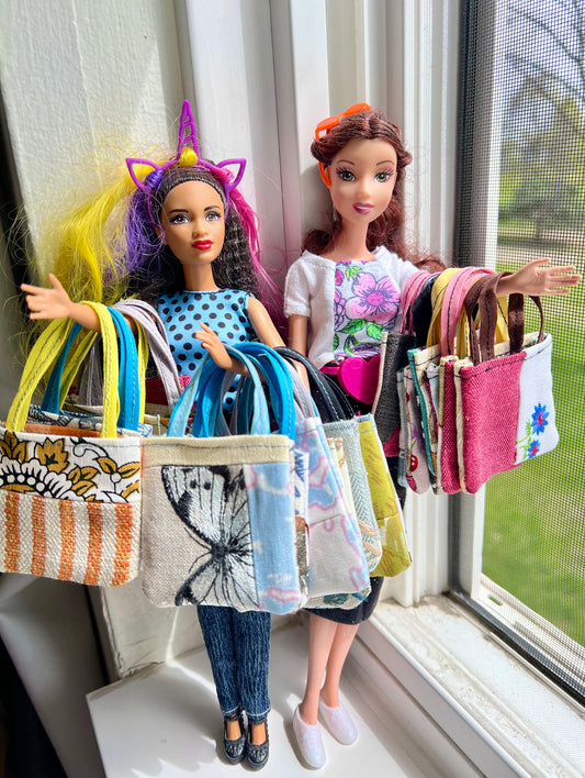 Two dolls holding handmade miniature tote bags by a window